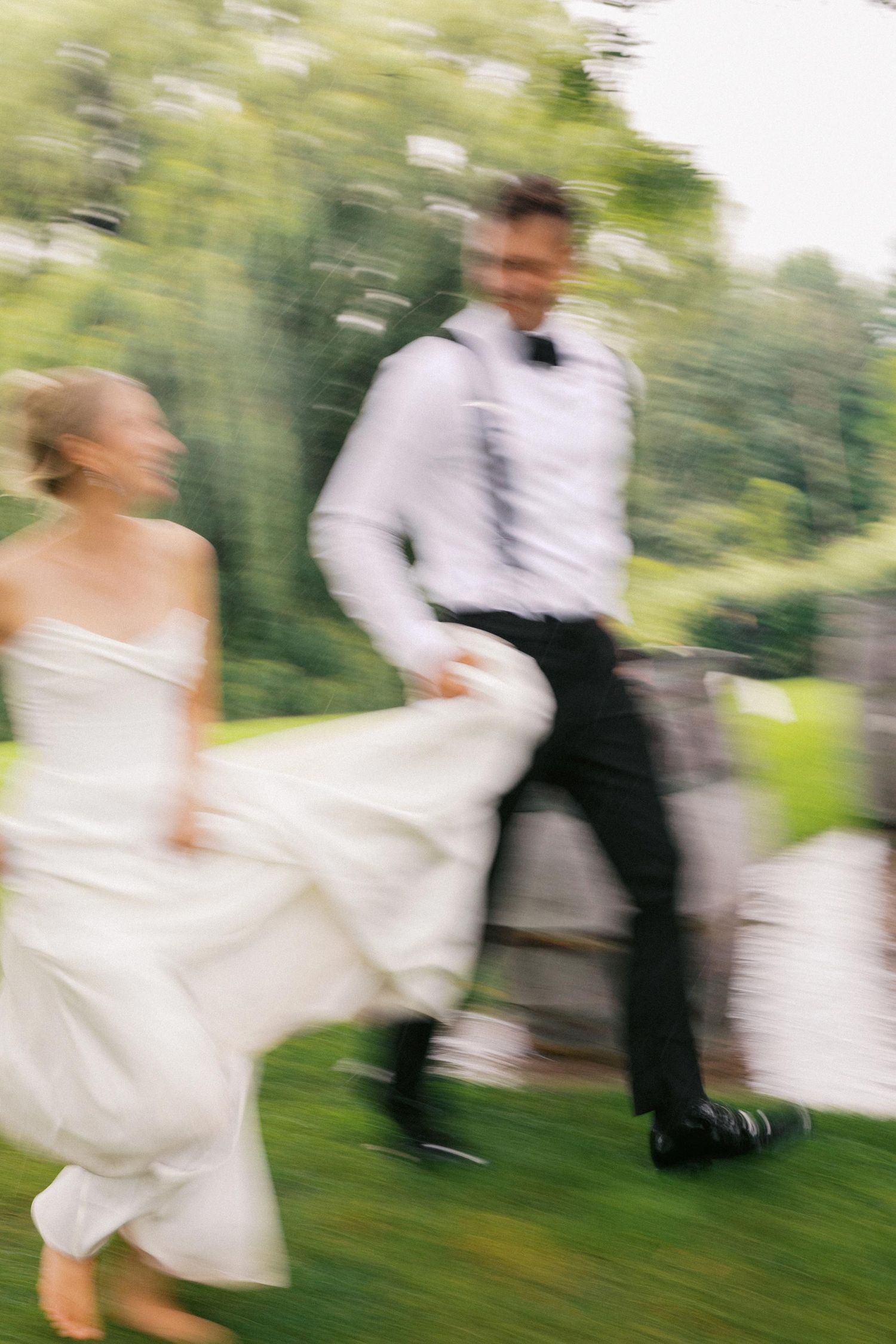Motion blur sequence of newlyweds dancing together outdoors in a garden setting with green foliage in background.