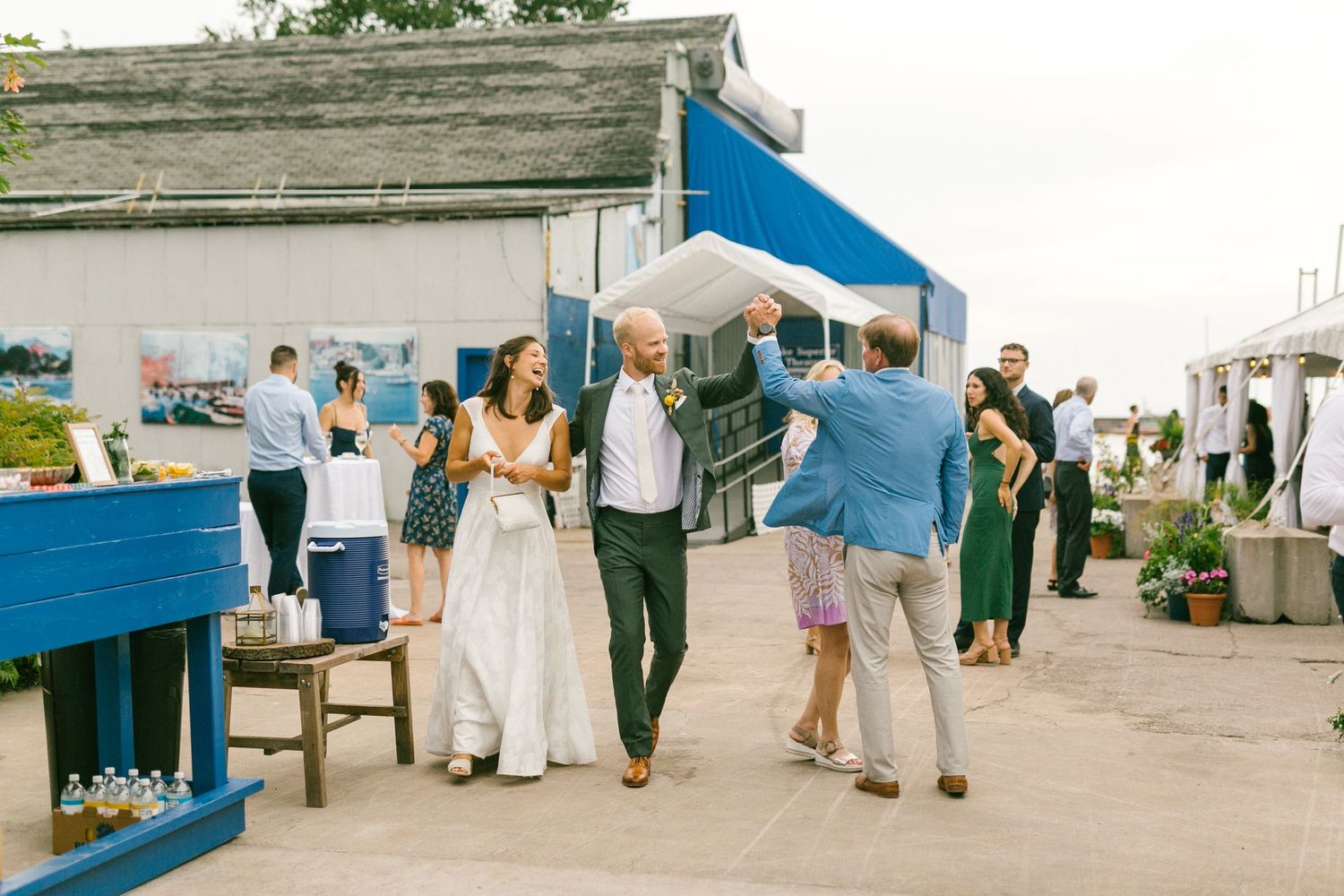 Outdoor wedding reception setup with white tables and chairs along a waterfront.