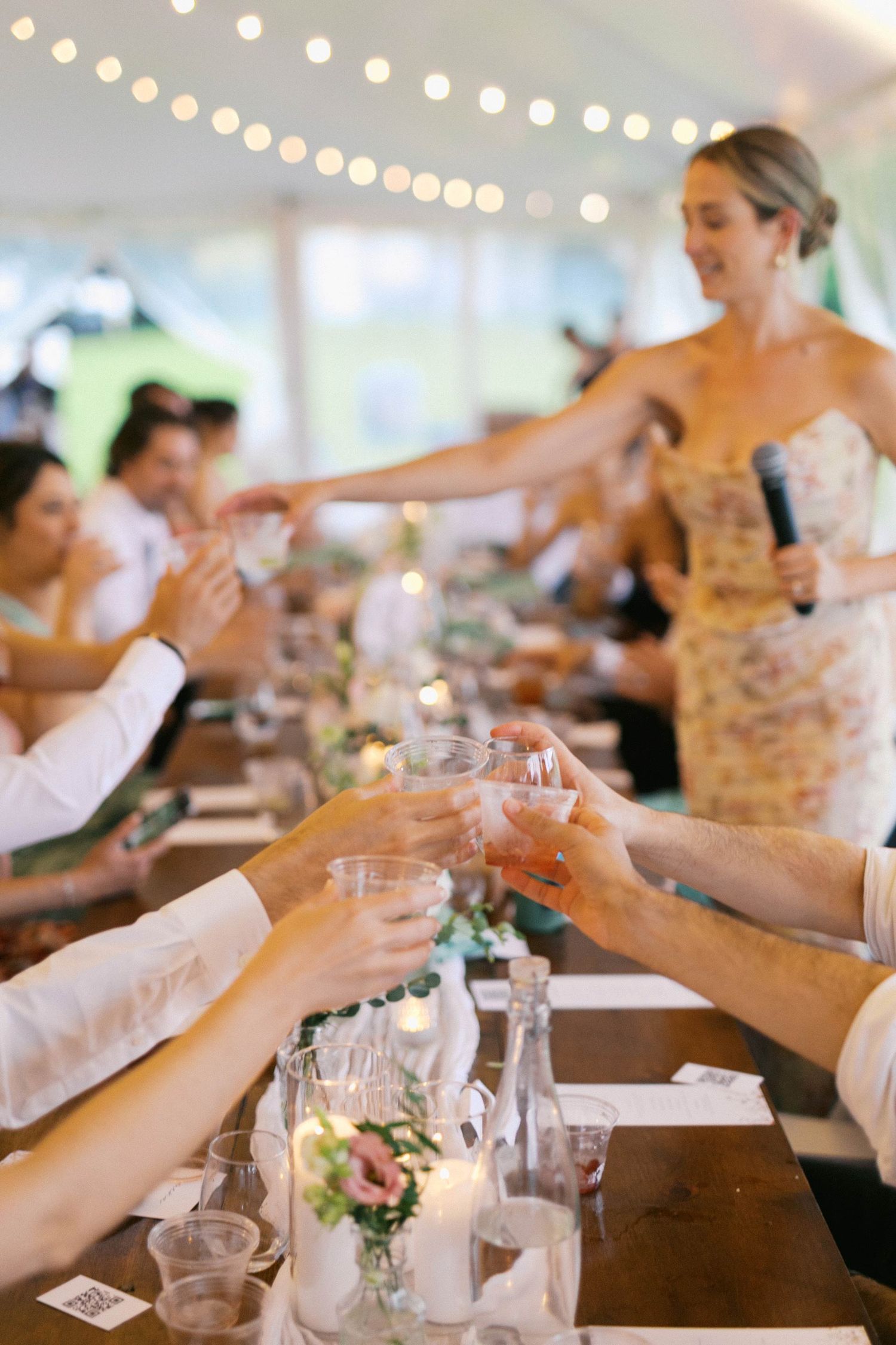People toasting and clinking wine glasses together across an elegant dining table at a celebratory event.