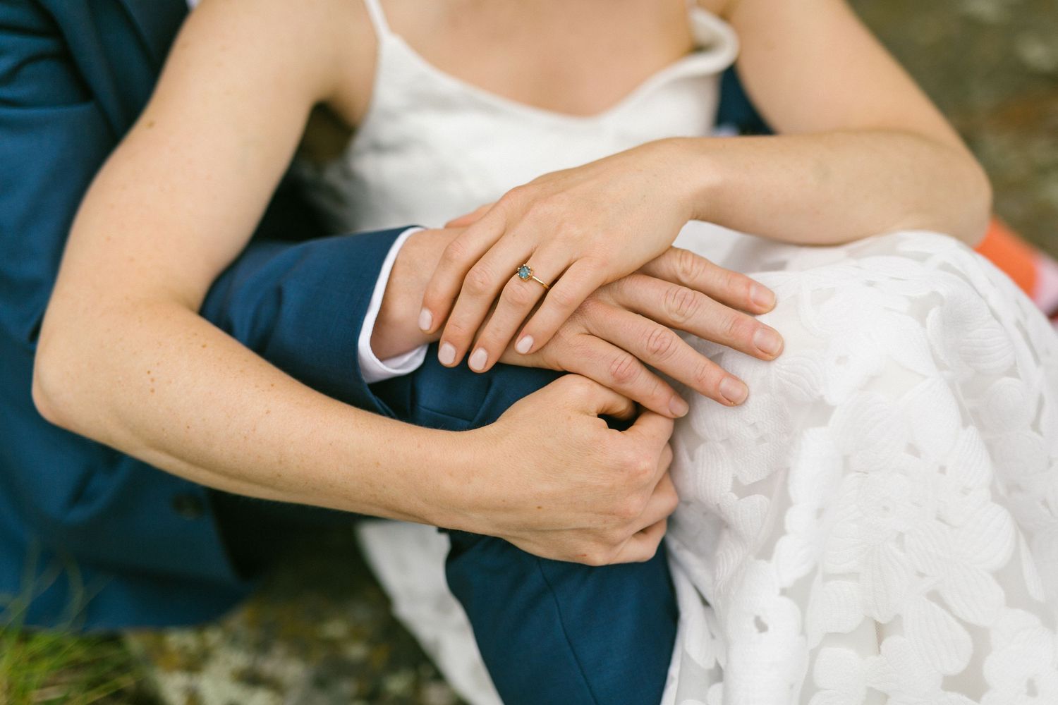 Close-up view of hands resting on white and navy blue fabric outdoors.