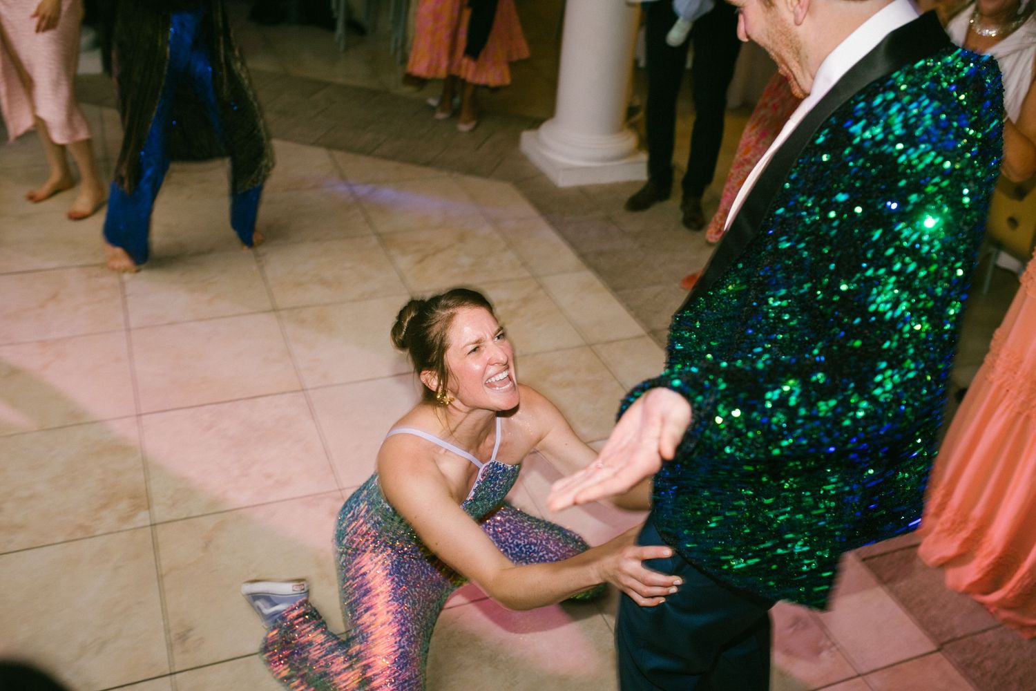 Dancers in sparkly attire move energetically across a tiled floor during a celebration event.