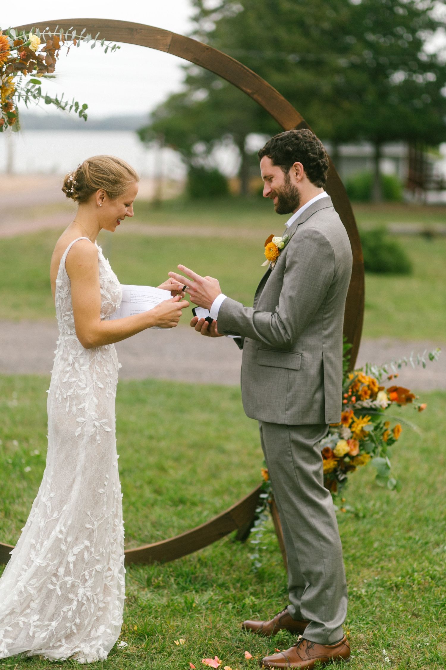 A couple shares a joyful moment under a circular arch decorated with autumn flowers.