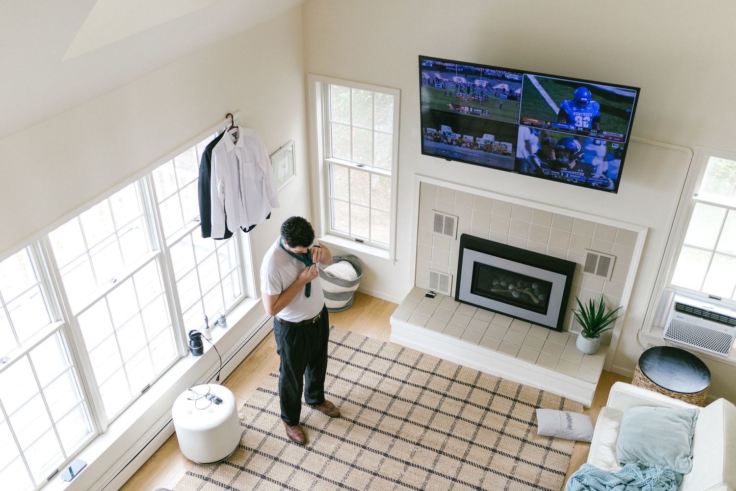 An overhead view of someone exercising with a fitness game on a large TV screen in a bright modern living room.