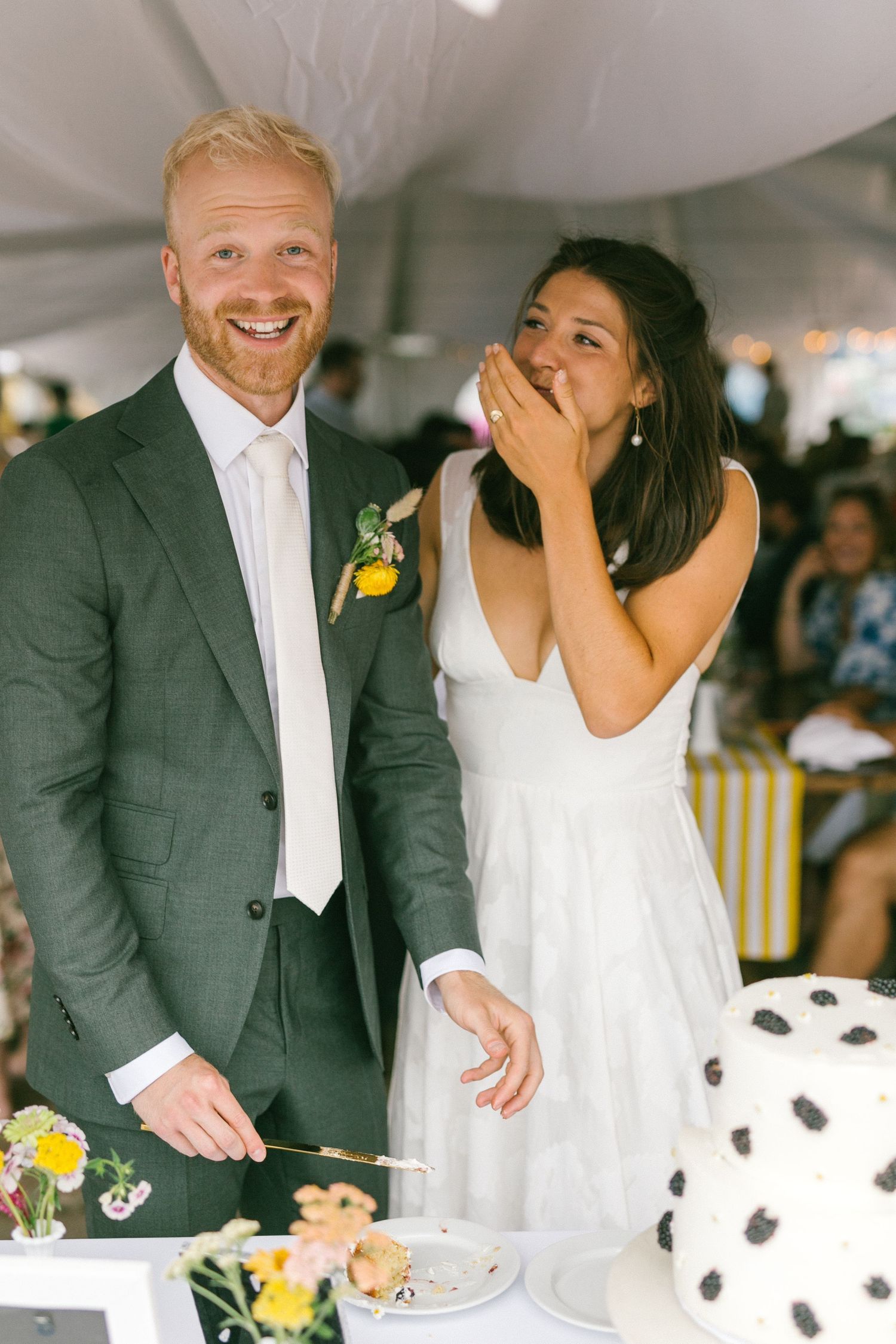 A couple shares a joyful moment while cutting their polka dot wedding cake.
