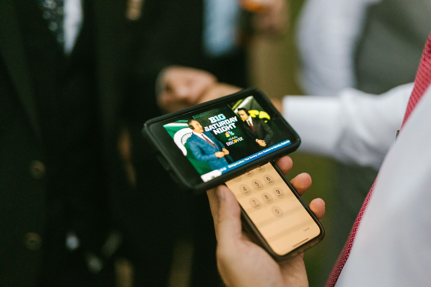 Close-up shot of hands holding a smartphone displaying wedding photos during the reception.