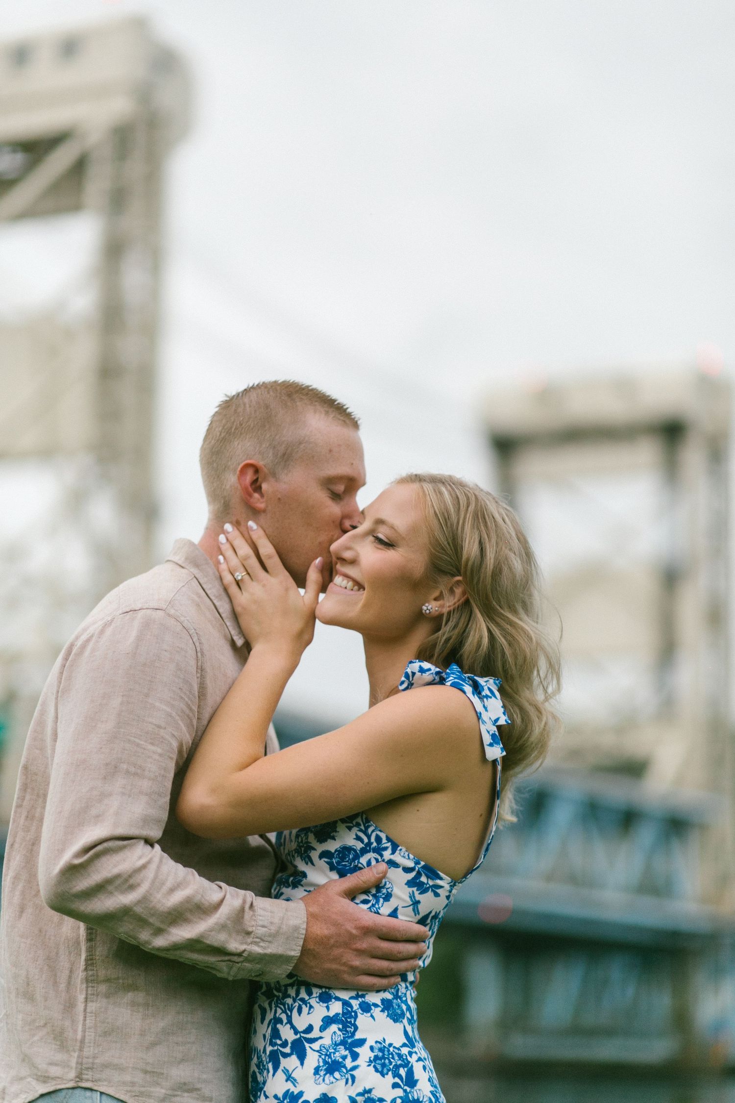 A loving couple in a tender embrace share a romantic kiss, with the woman wearing a blue floral dress.