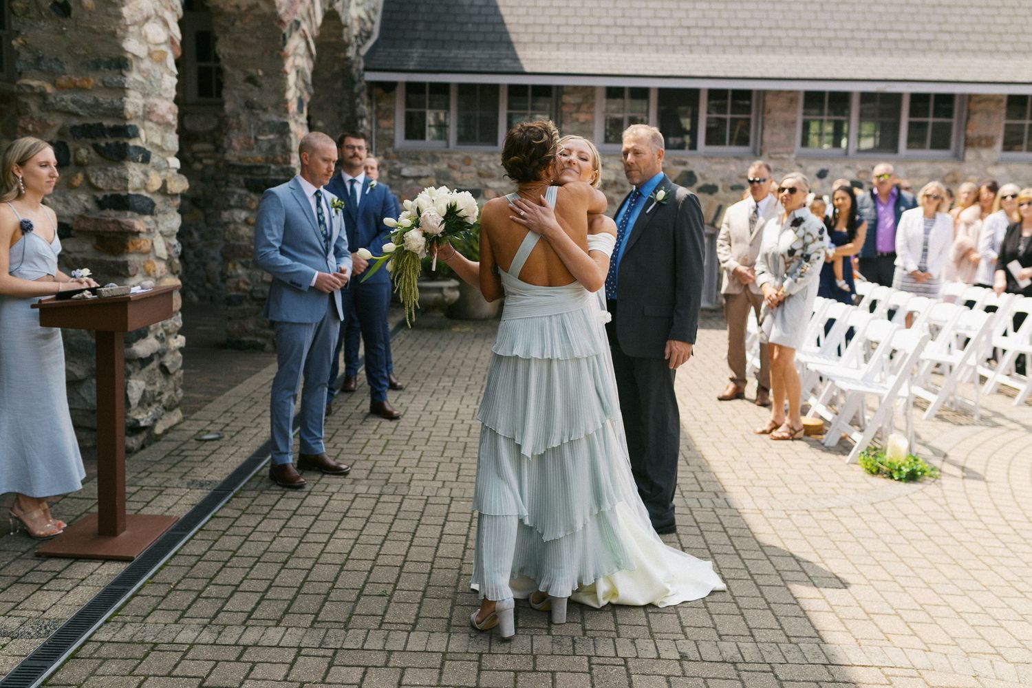 Outdoor wedding ceremony with guests gathered on a stone patio.