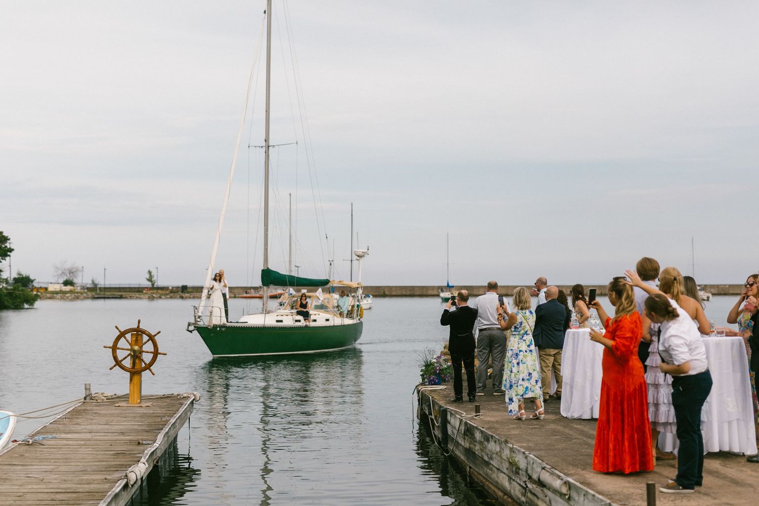 Wedding guests celebrate on a dock with boats in the background.