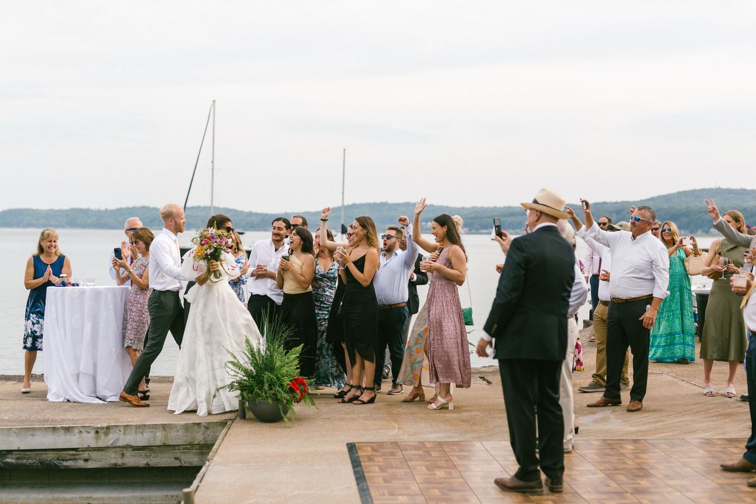 Wedding guests mingling on a waterfront deck during a celebration.