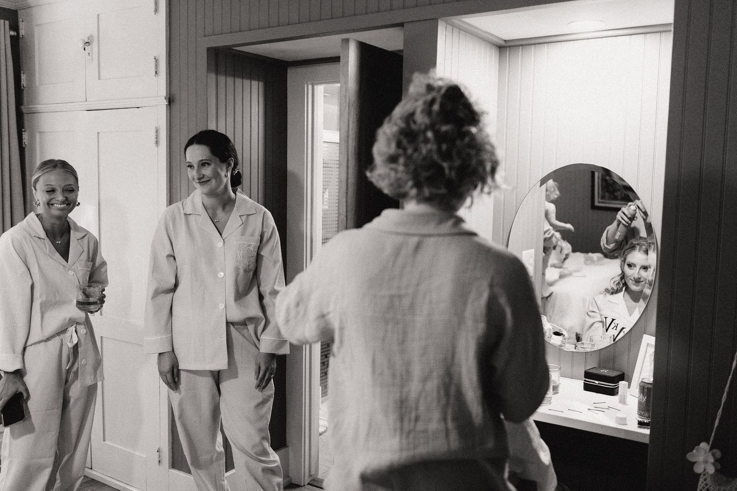 People in formal attire preparing in a hallway with white doors and walls.