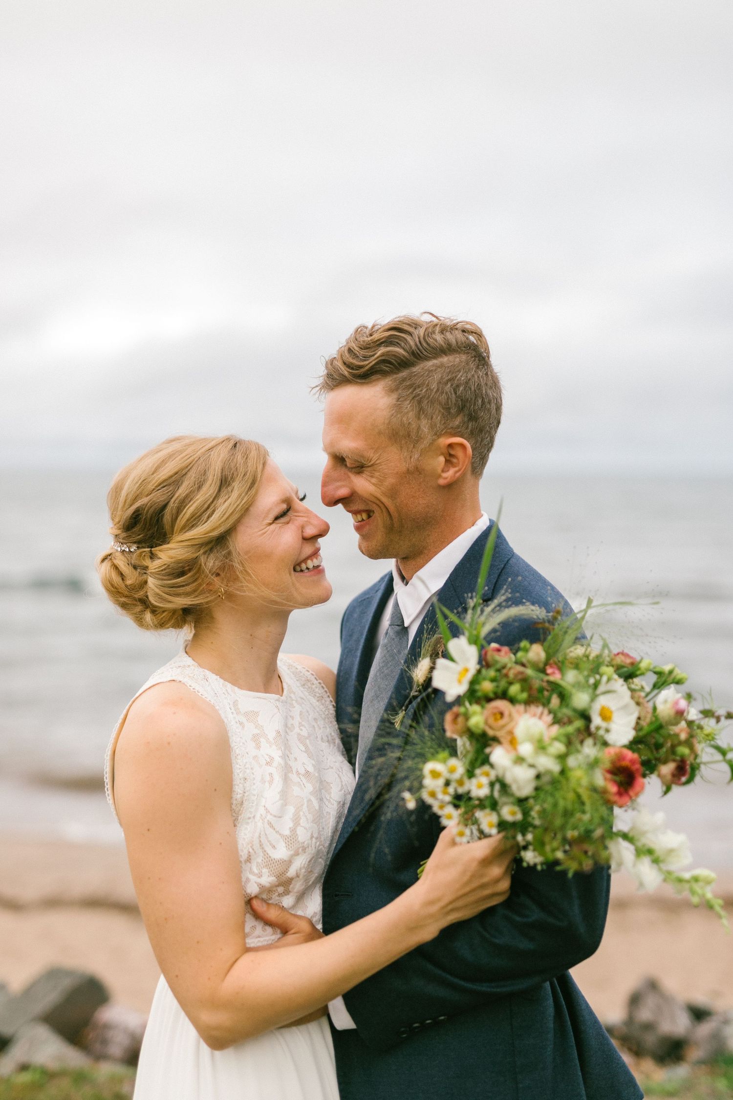 A romantic beach wedding portrait with a beautiful bouquet against an overcast sky.