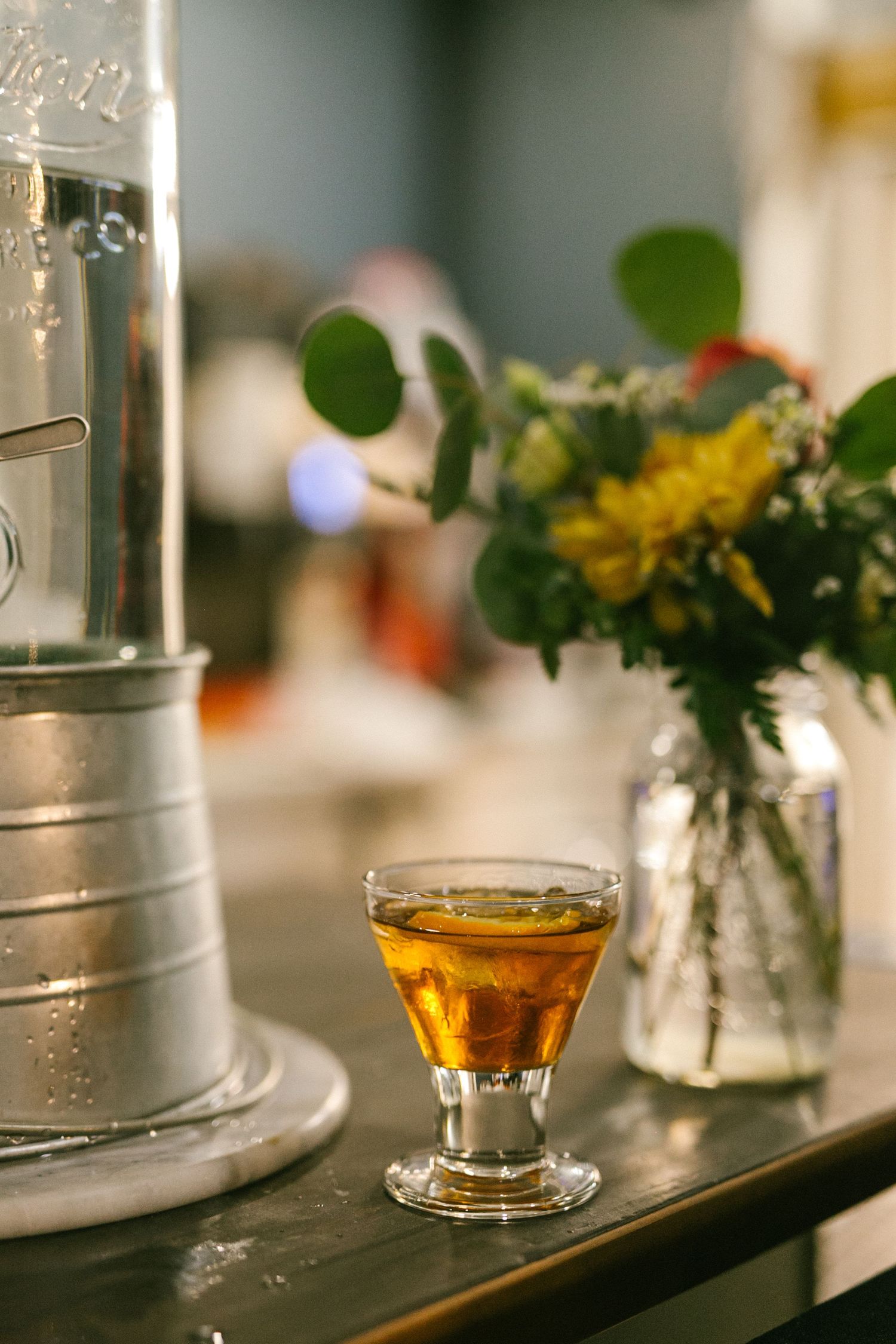 Elegant table setting with a cocktail glass and flower arrangement in a mason jar.