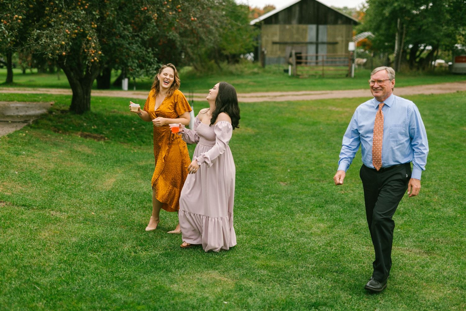 Wedding guests walking across a green lawn in formal attire on a sunny day.