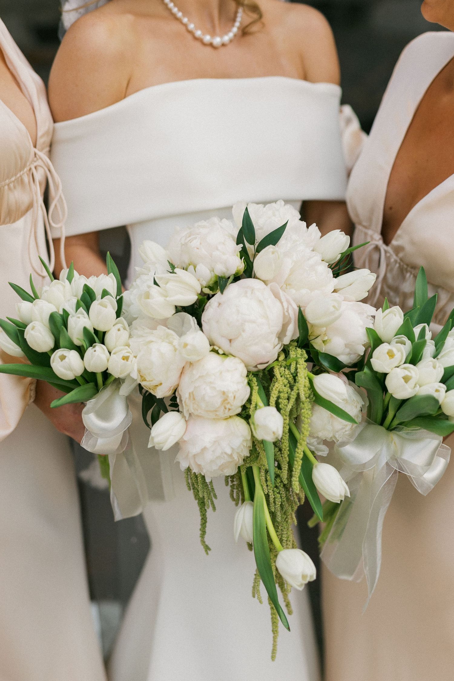 An elegant row of white floral bouquets with peonies, roses and greenery accents.