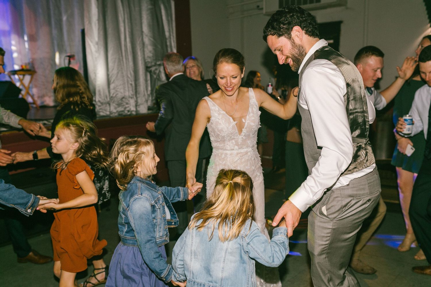 Wedding reception attendees dancing together on a dance floor with children joining in the celebration.