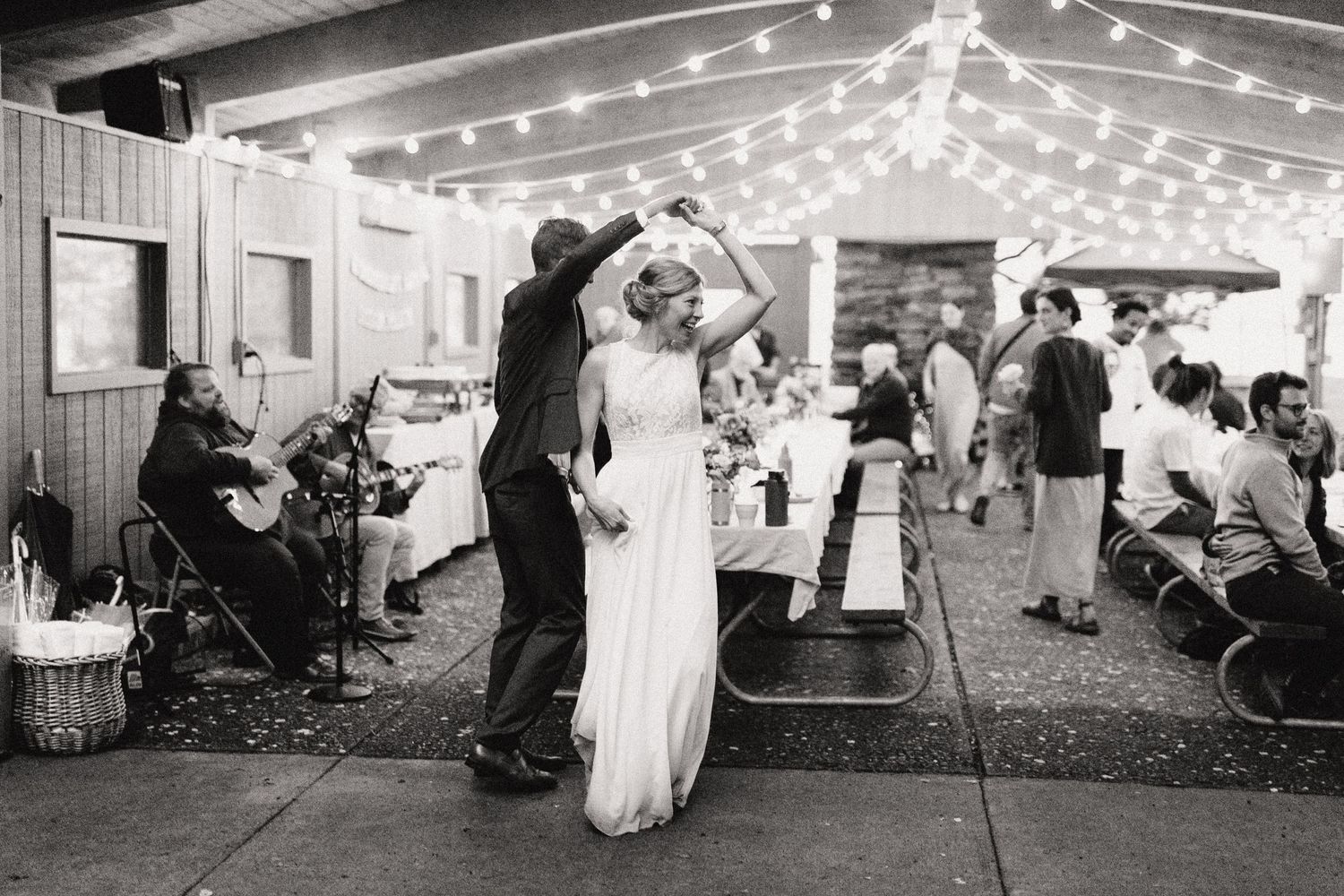 Wedding couple dancing on outdoor patio decorated with string lights.