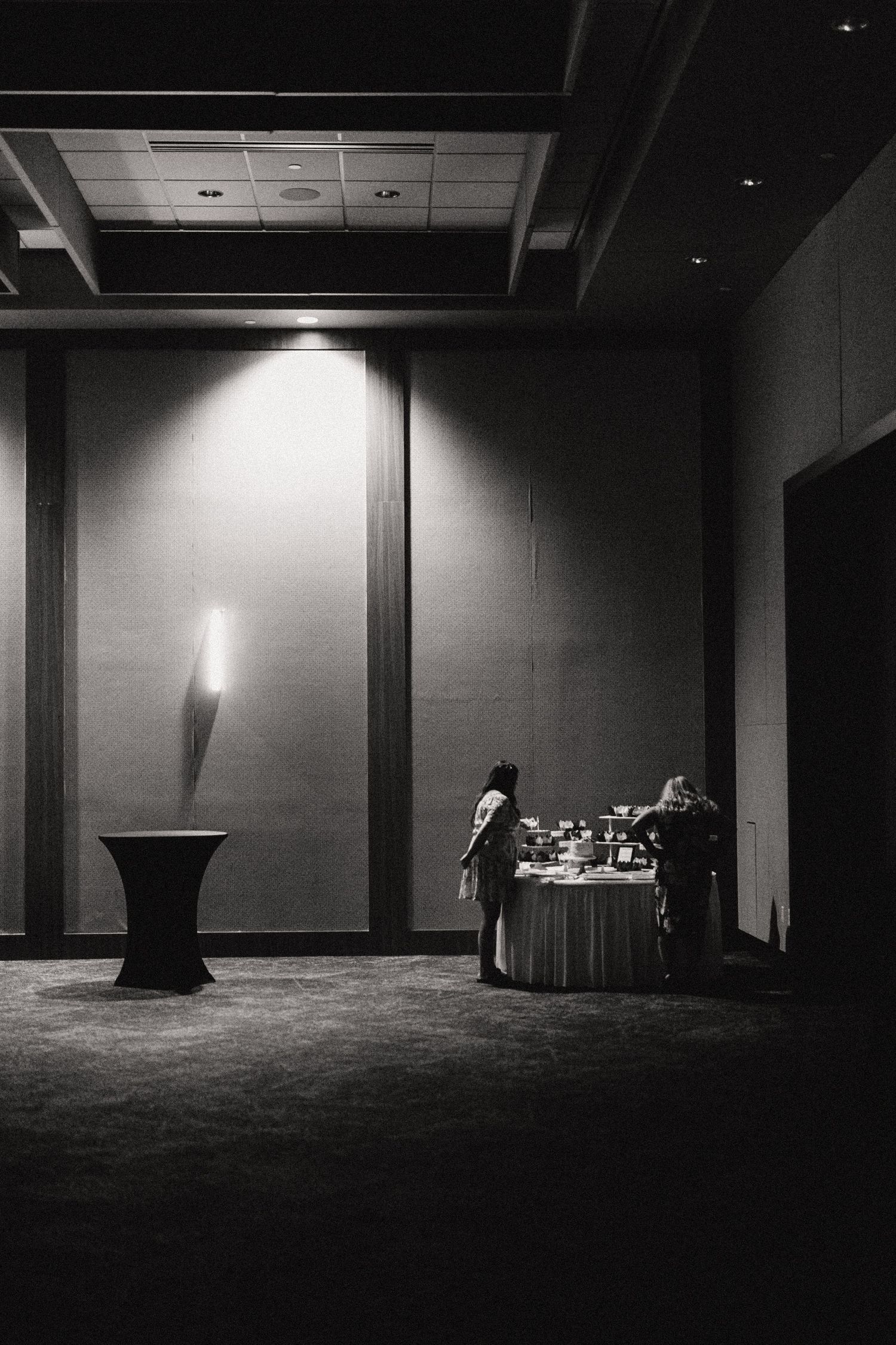 A dramatic black and white series of empty conference rooms with minimal lighting creating stark shadows and contrast.