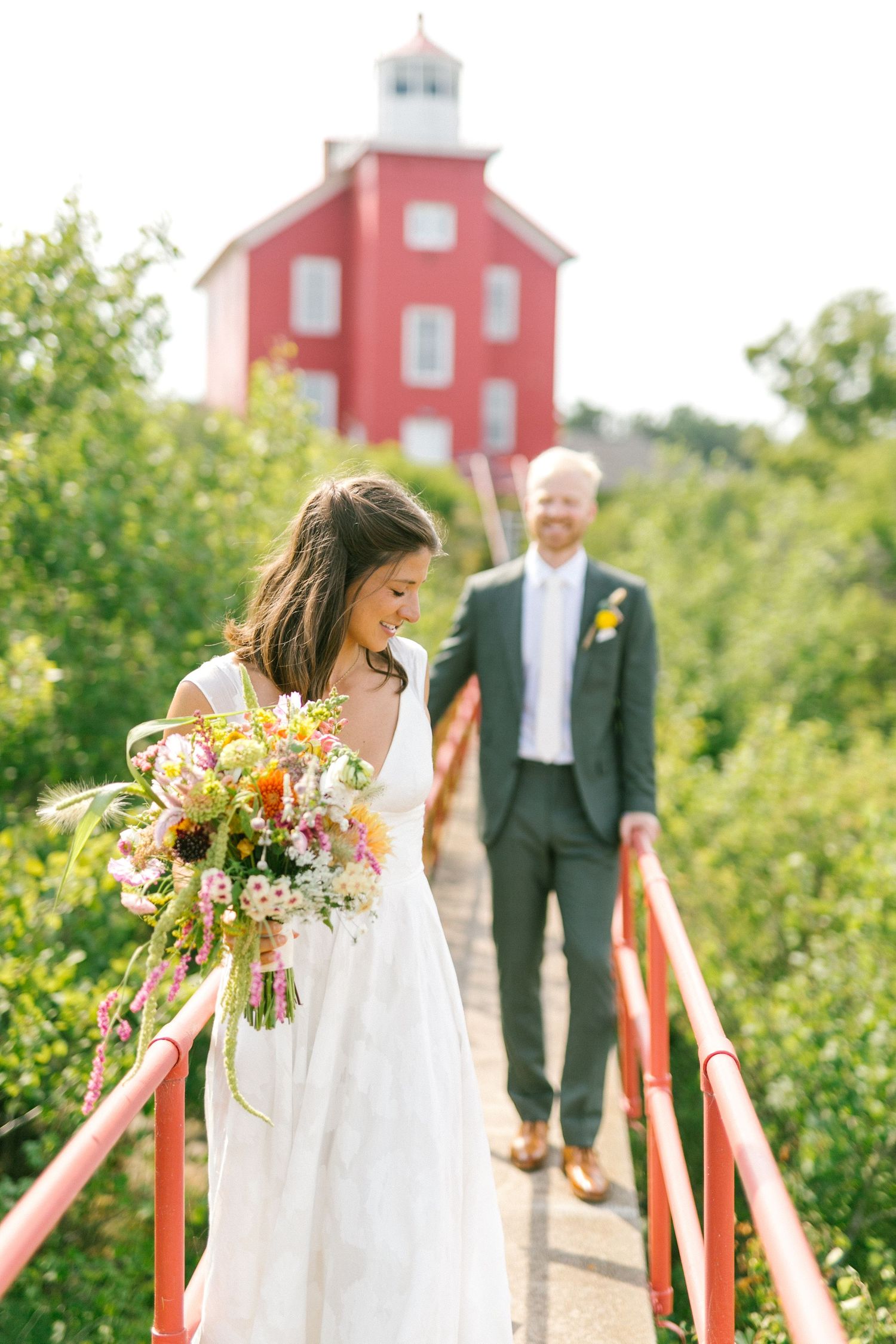 A red lighthouse chapel stands prominently against lush green foliage on a sunny summer day.