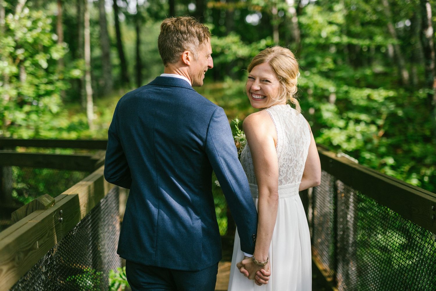 Couple sharing intimate moment on wooden bridge surrounded by lush forest scenery.