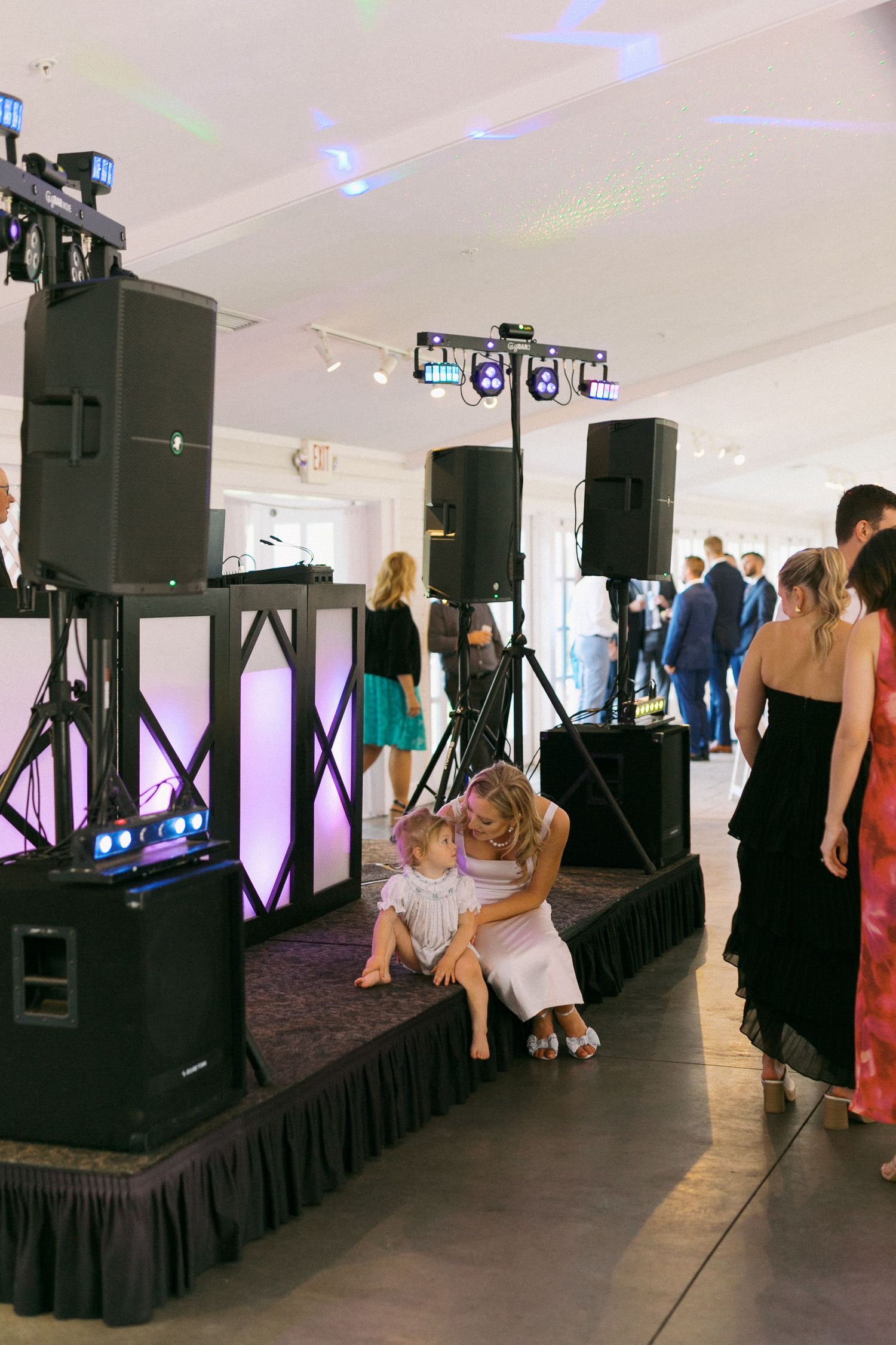 Professional audio and lighting equipment set up on black-skirted platforms at an indoor event space.