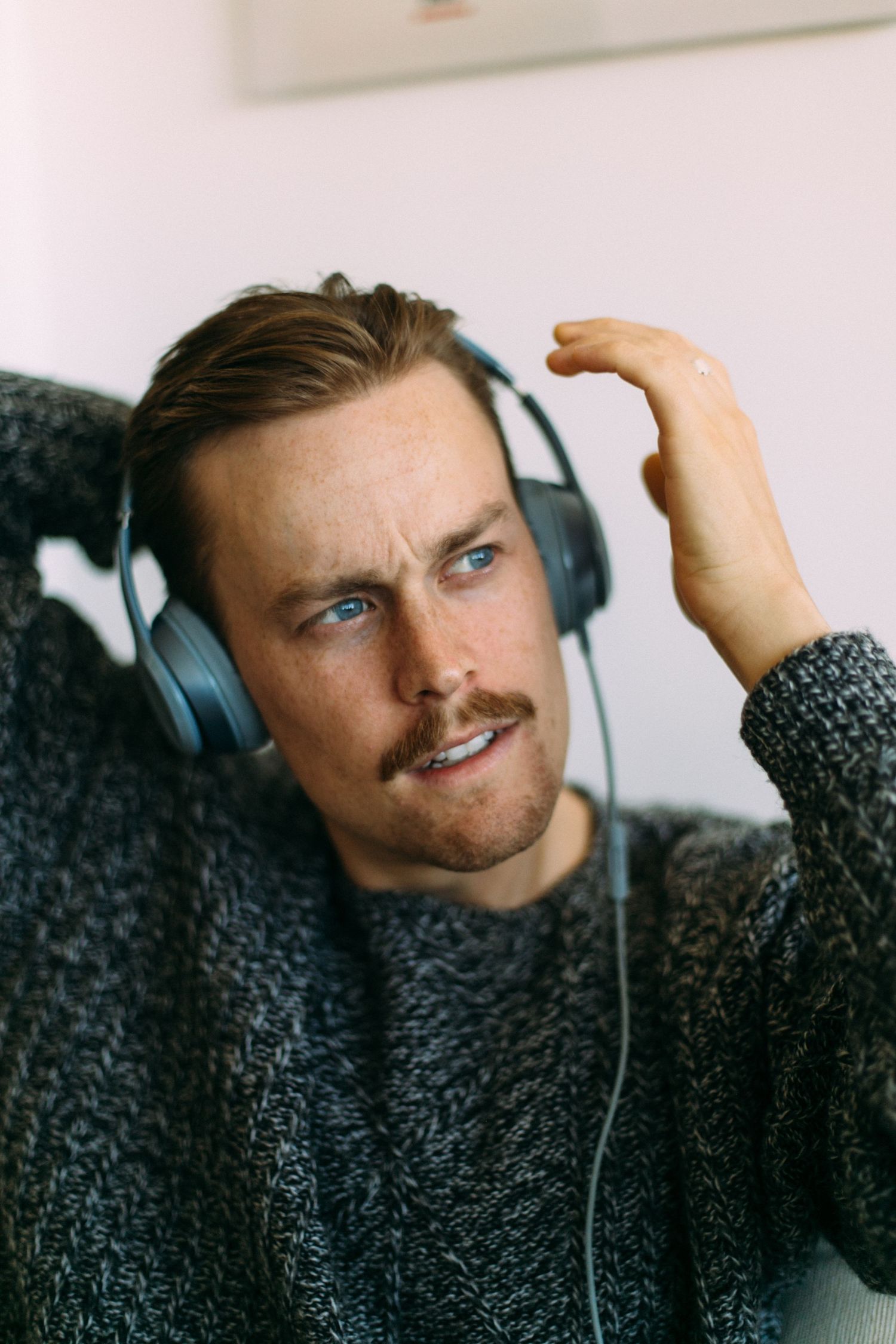 Close-up portrait of someone wearing headphones against a white wall.