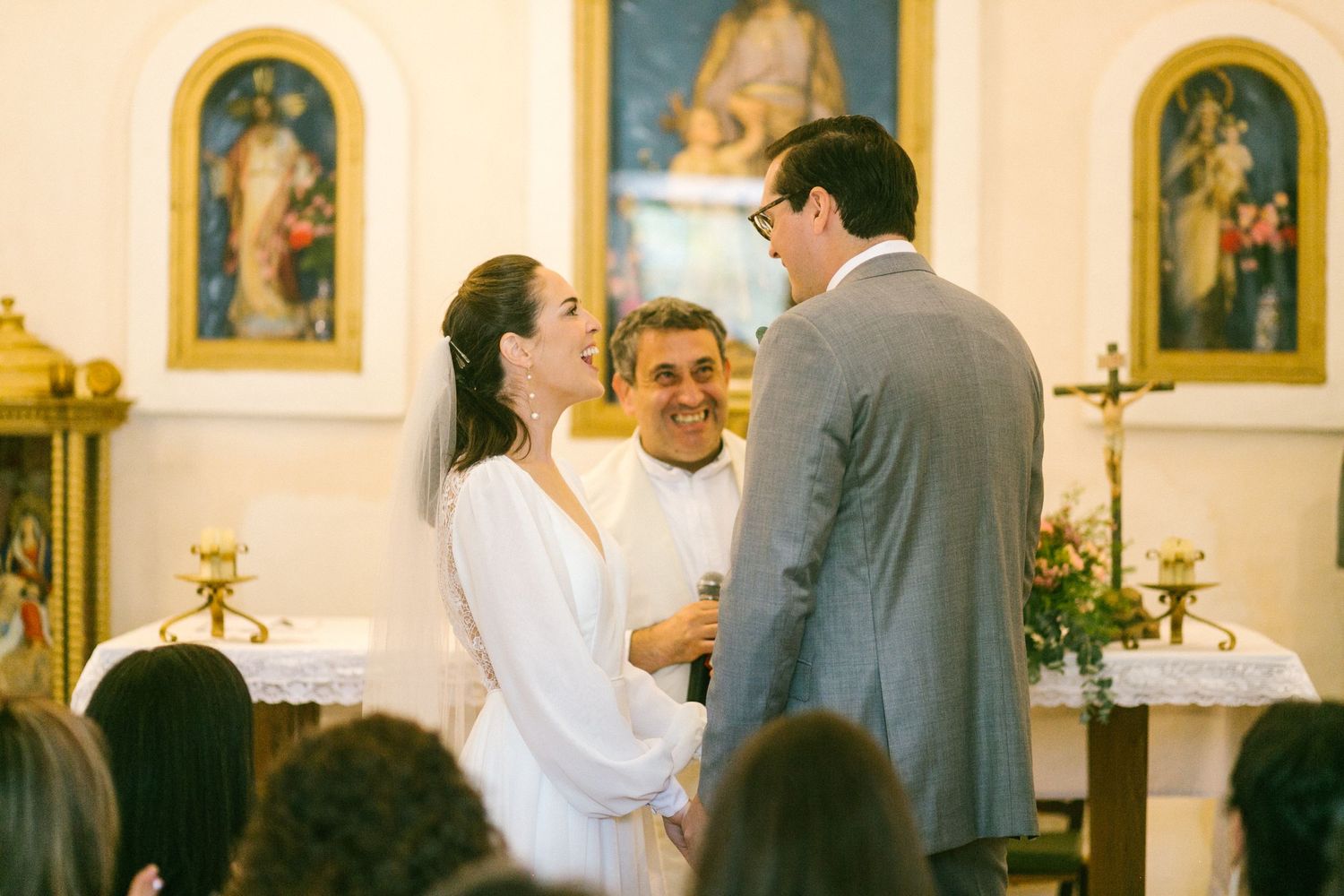 A couple stands at an altar during a traditional Catholic church wedding ceremony inside an ornate sanctuary.