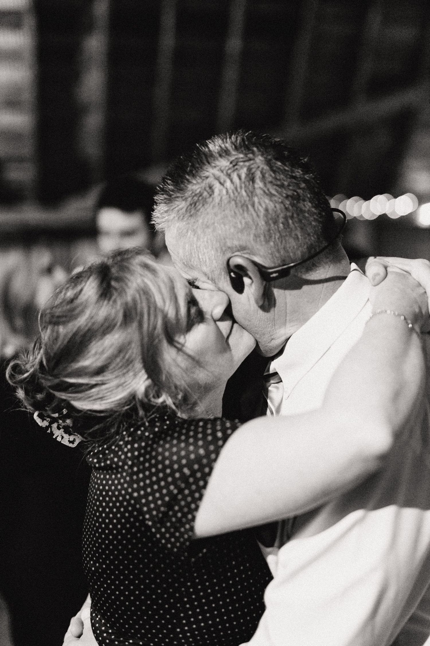 Intimate black and white photo of a couple dancing at an indoor celebration.