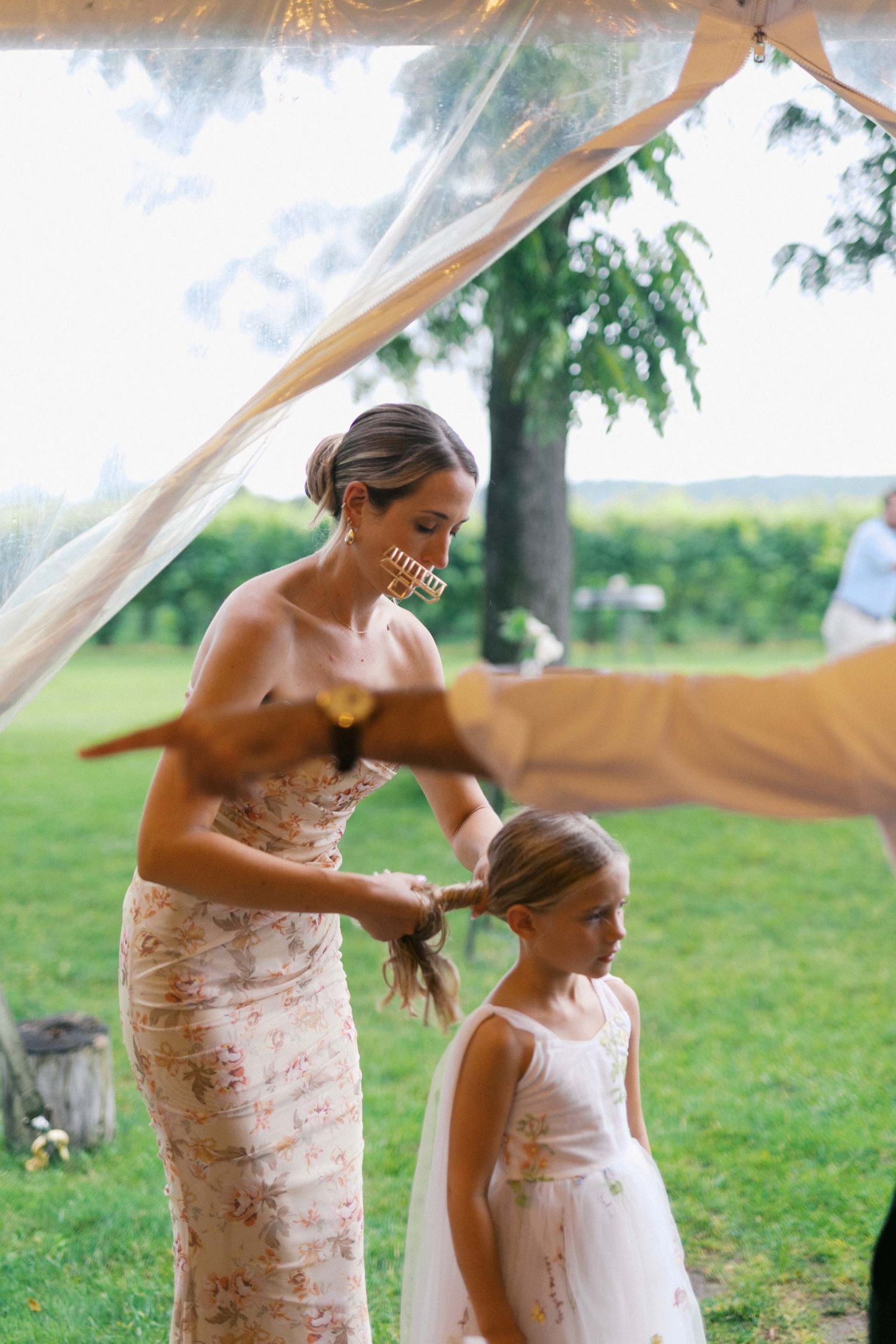 A touching moment between two people in matching pink dresses at an outdoor wedding celebration.