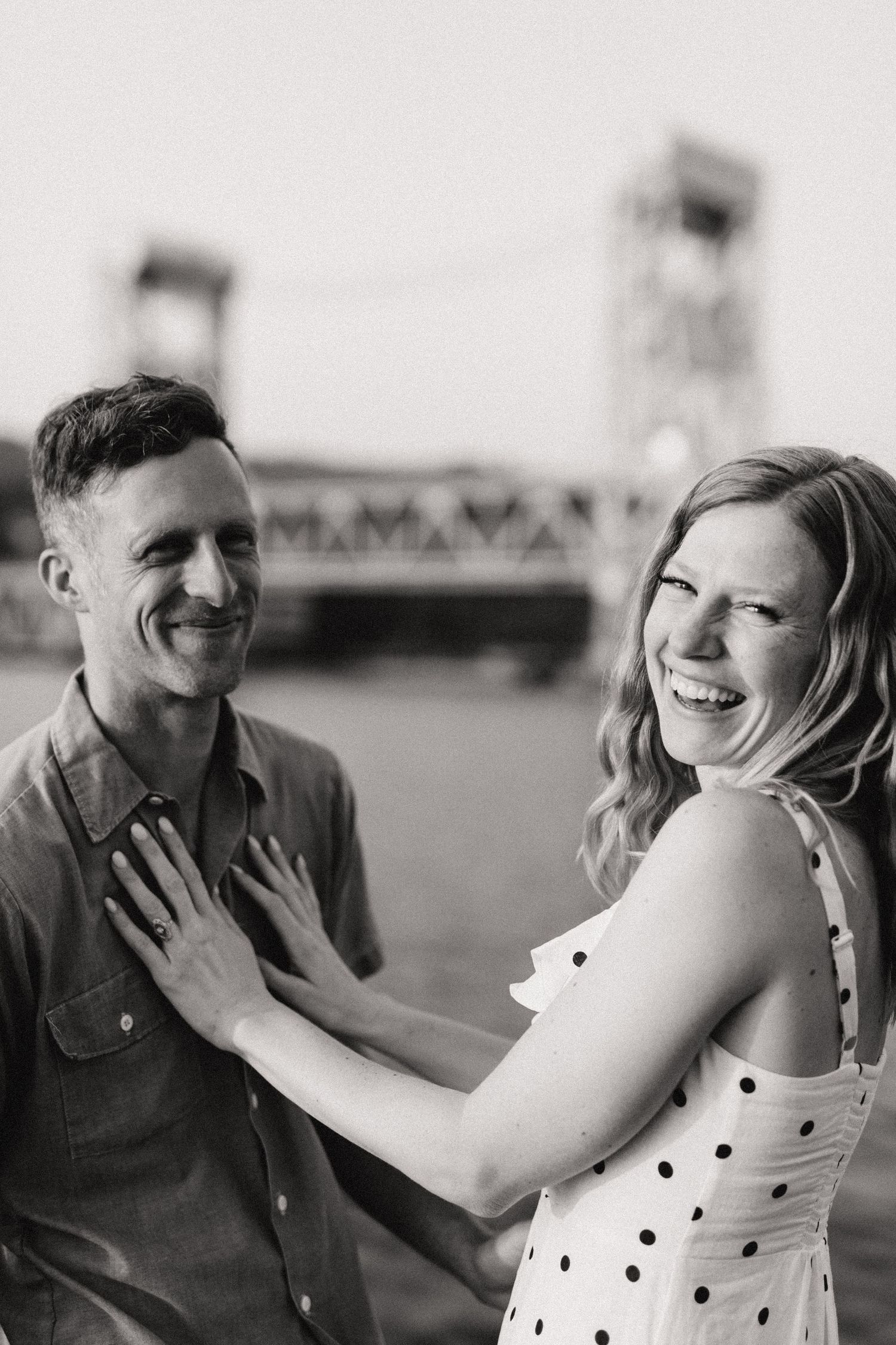 Black and white portrait of a laughing couple by the river.