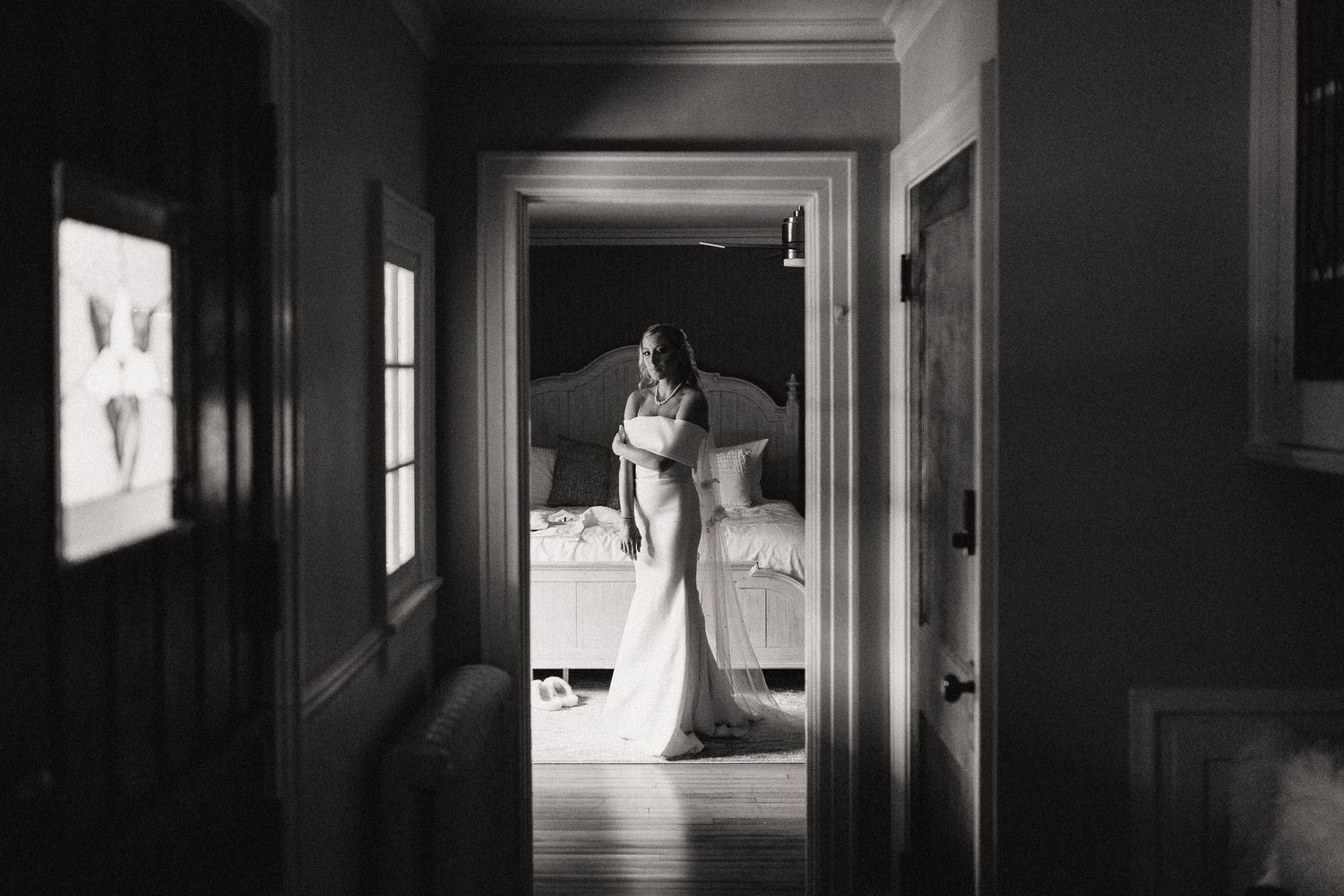Long empty hallway with vintage wooden doors and molding features dramatic black and white photography.