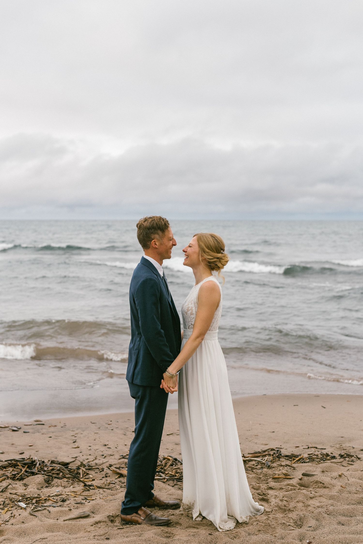 A serene beach wedding portrait with dramatic cloudy skies and rolling waves.