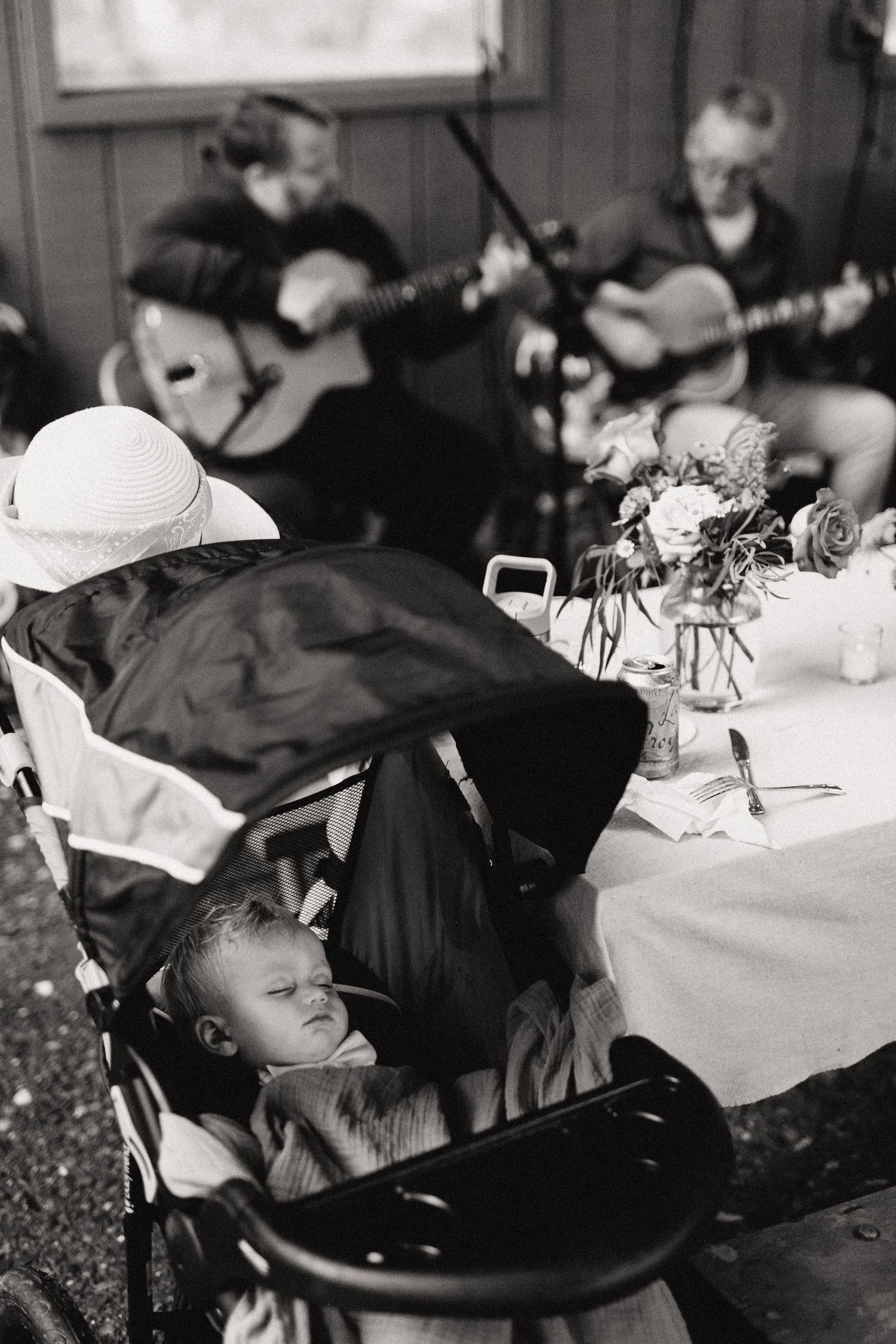 Musicians play guitars at an outdoor event while a child rests in a chair.