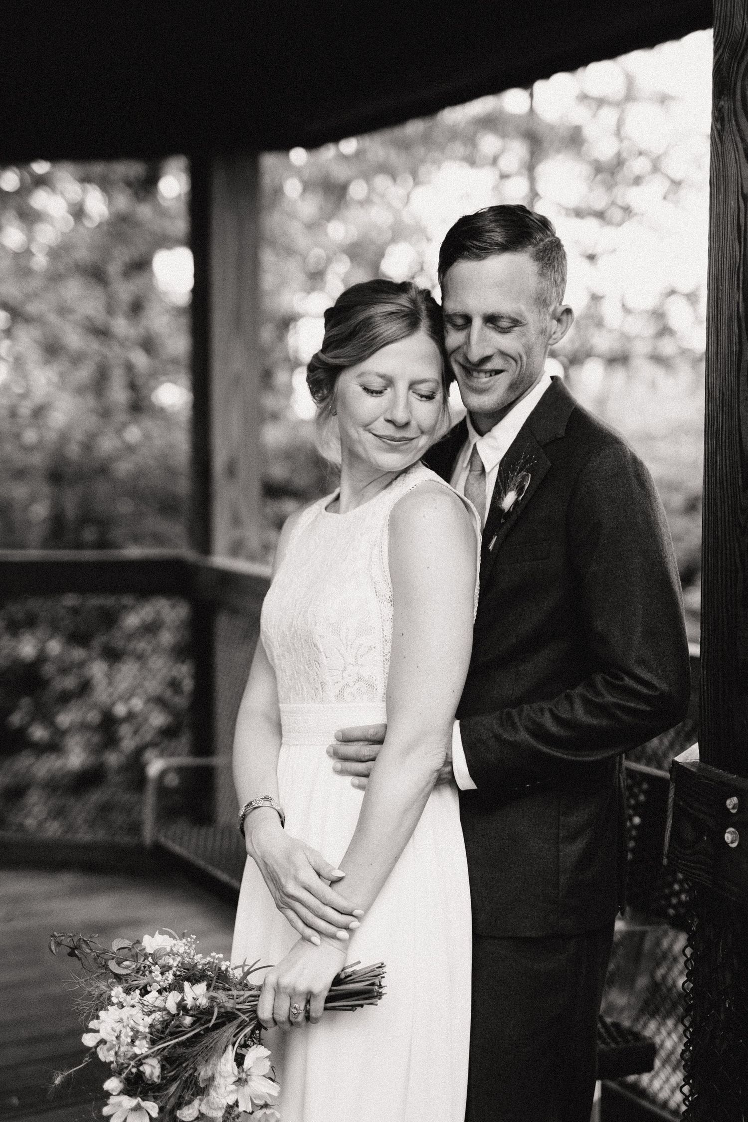 A tender wedding moment captured in black and white on a covered porch.