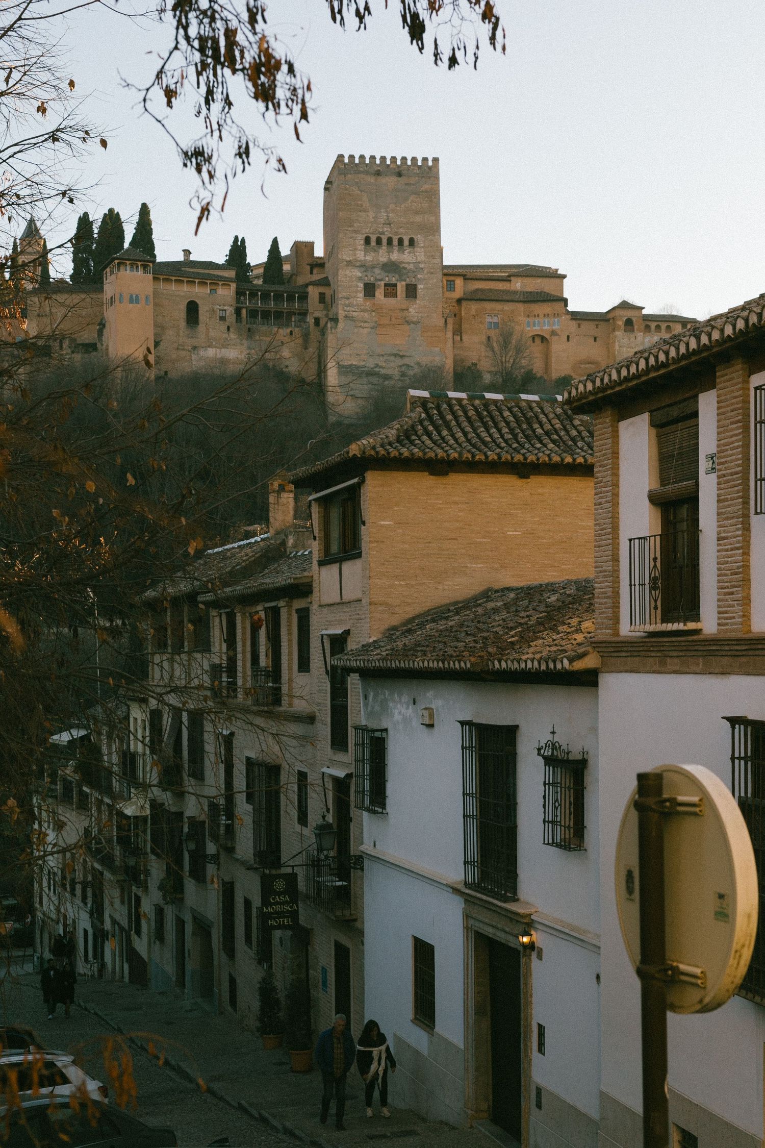 A steep cobblestone street in Granada's old town leads up to the historic Alhambra fortress.
