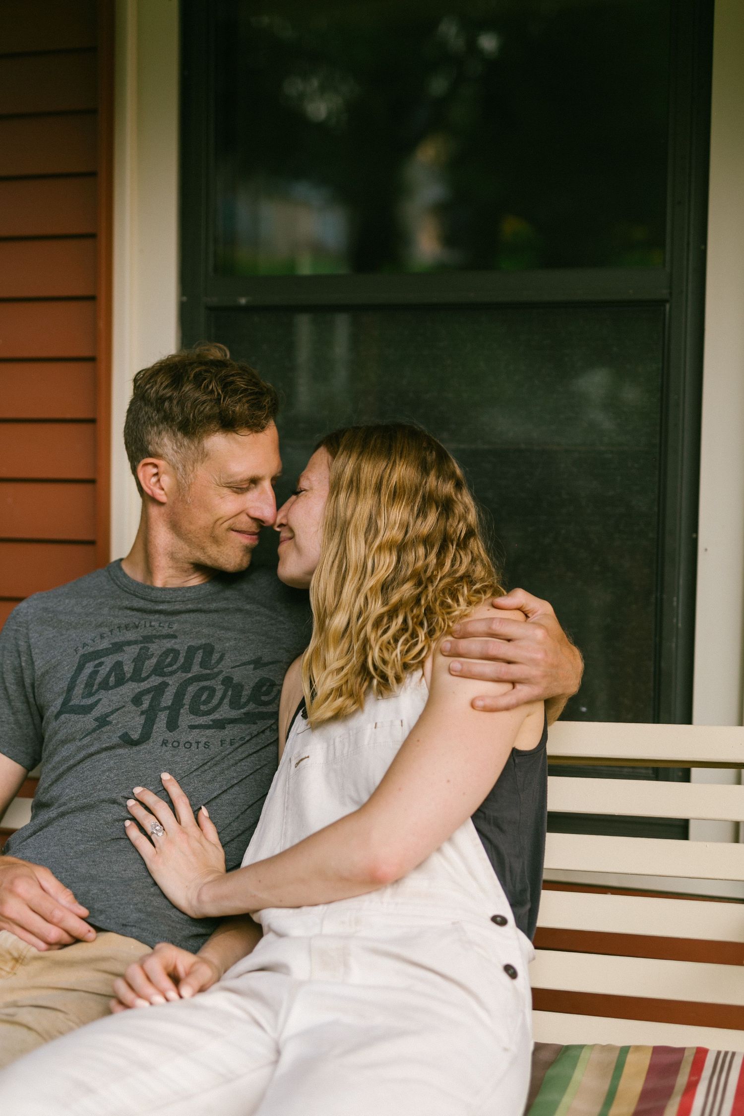 Couple sharing a tender moment while sitting on a porch bench.