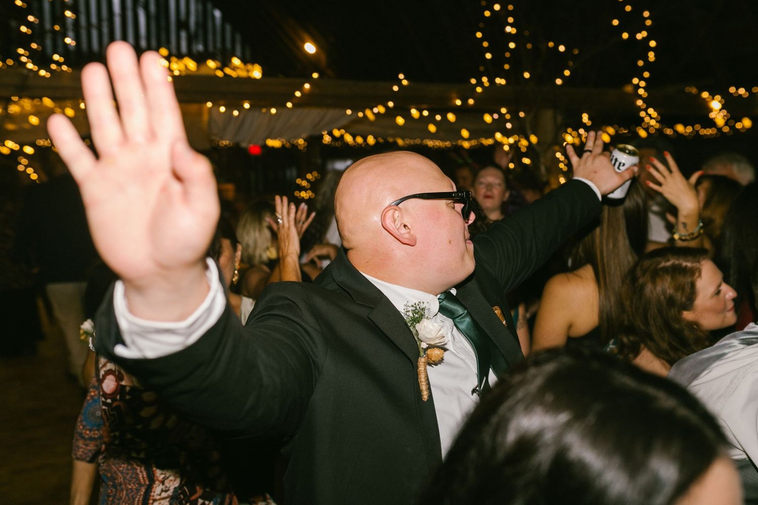 Guest dancing enthusiastically at a wedding reception with string lights illuminating the venue.