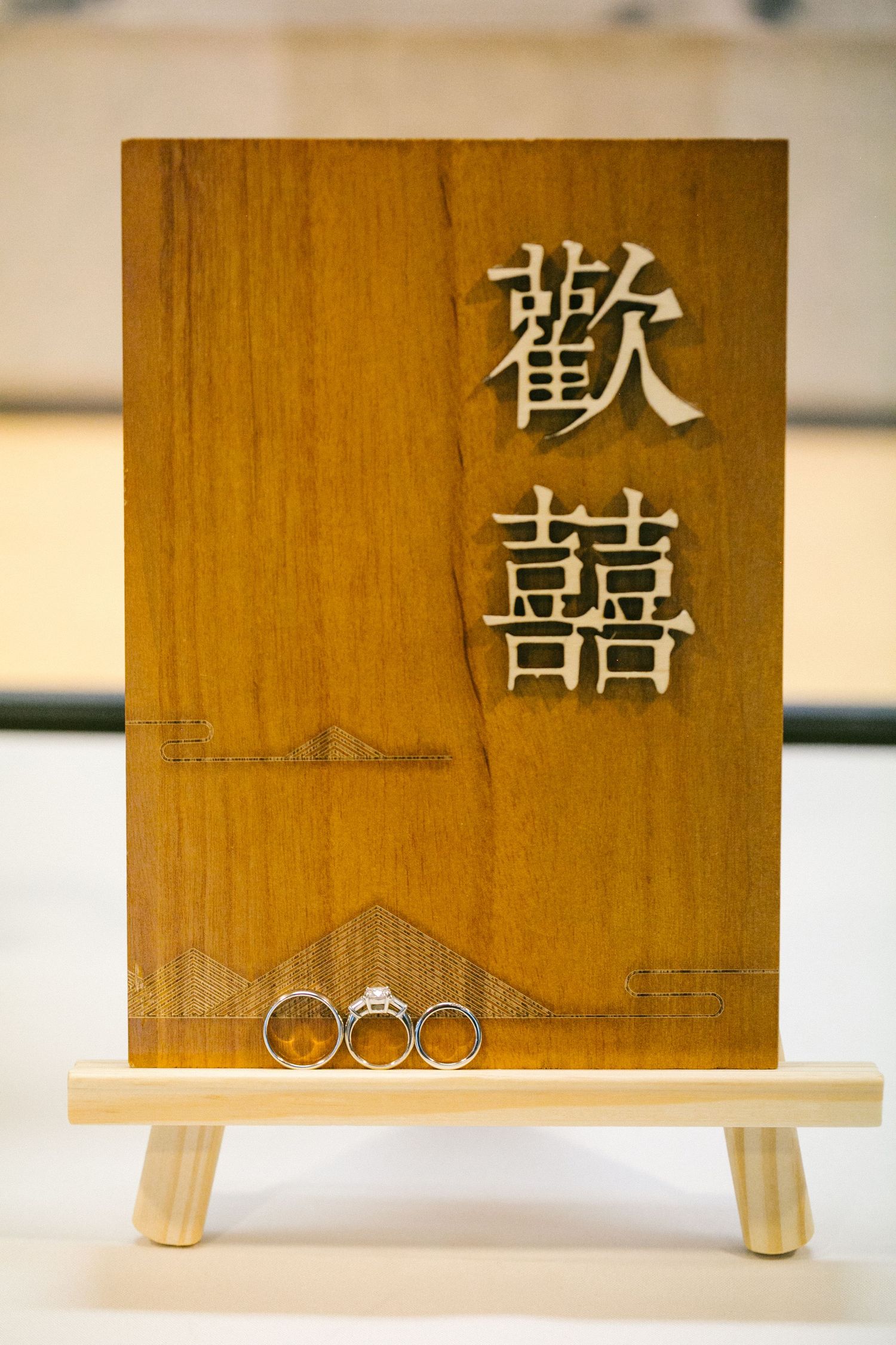 Wooden wedding sign with Chinese characters and two wedding rings displayed on a small easel.