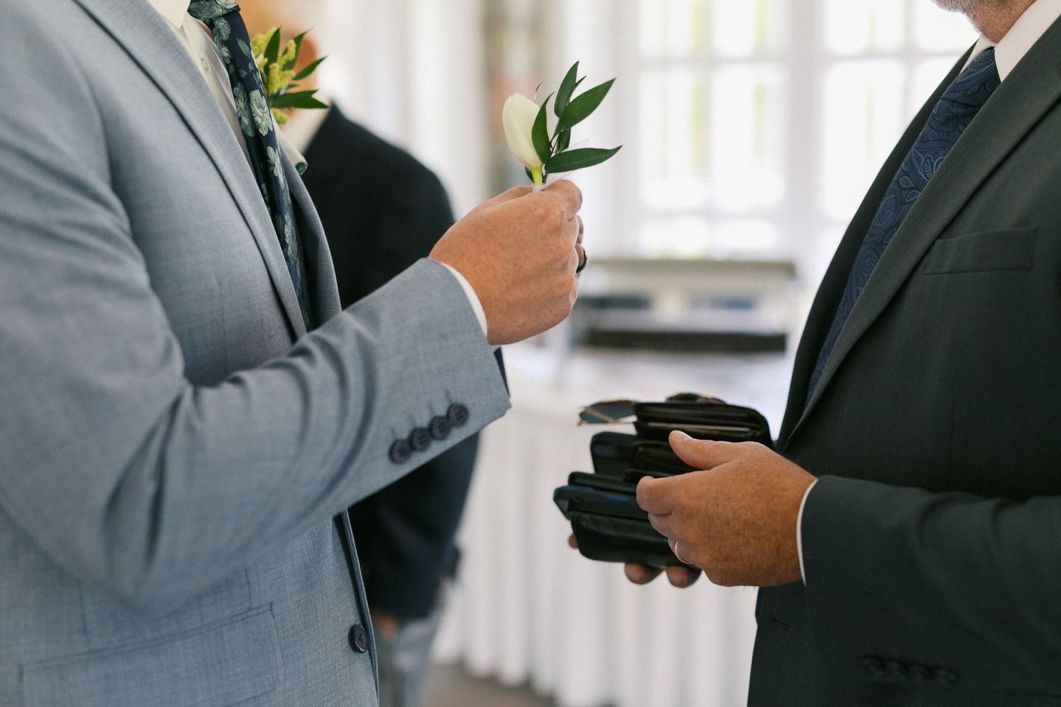 Detail shots of formal attire with boutonnieres and suits at a wedding celebration.
