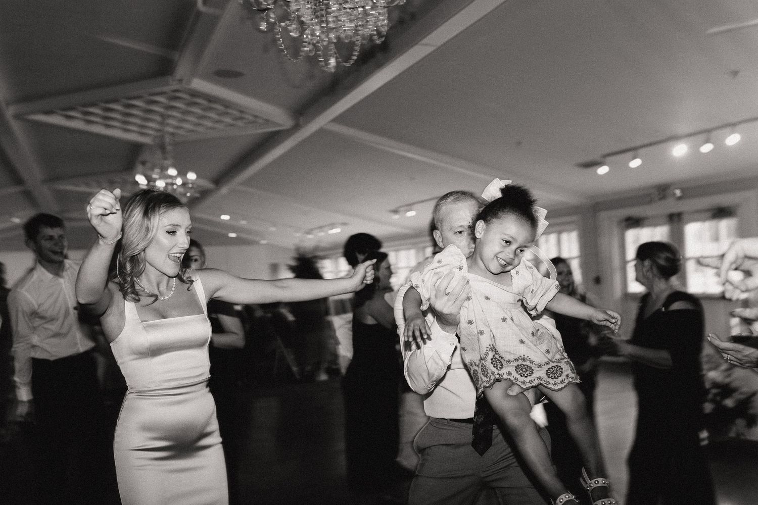 Guests dancing and celebrating under a crystal chandelier at an elegant reception venue.