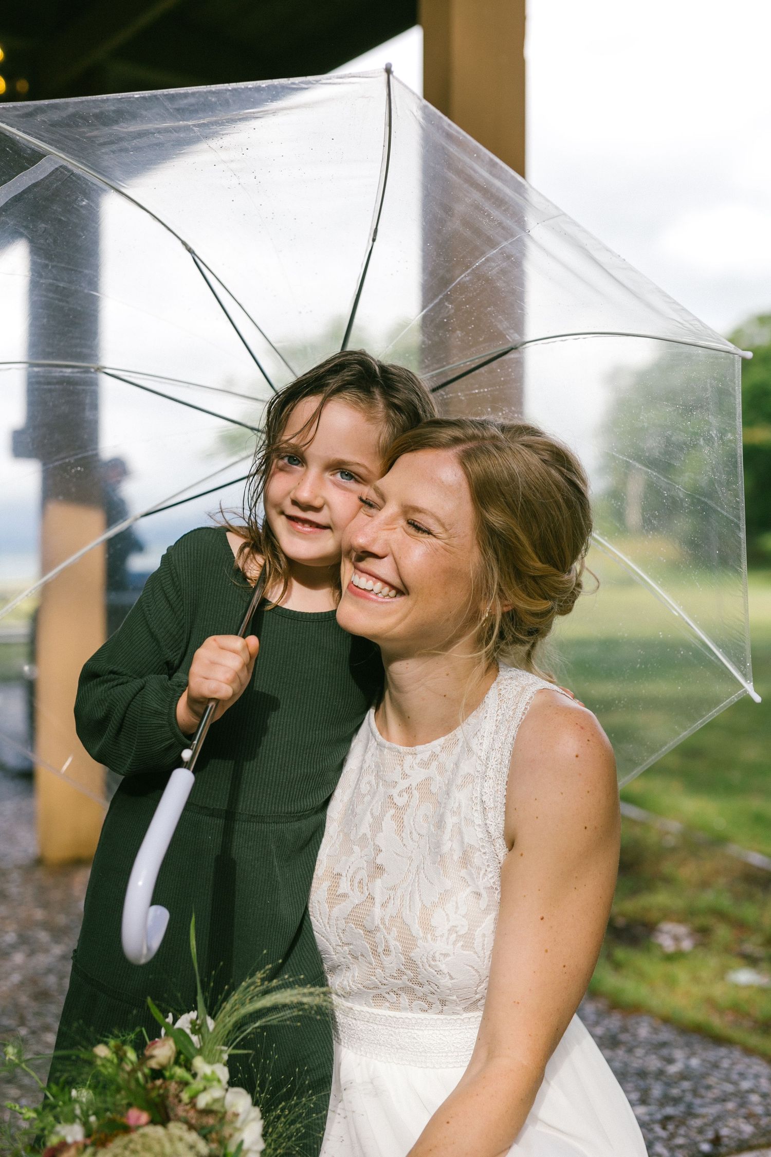A joyful moment shared under a clear umbrella during a wedding celebration.