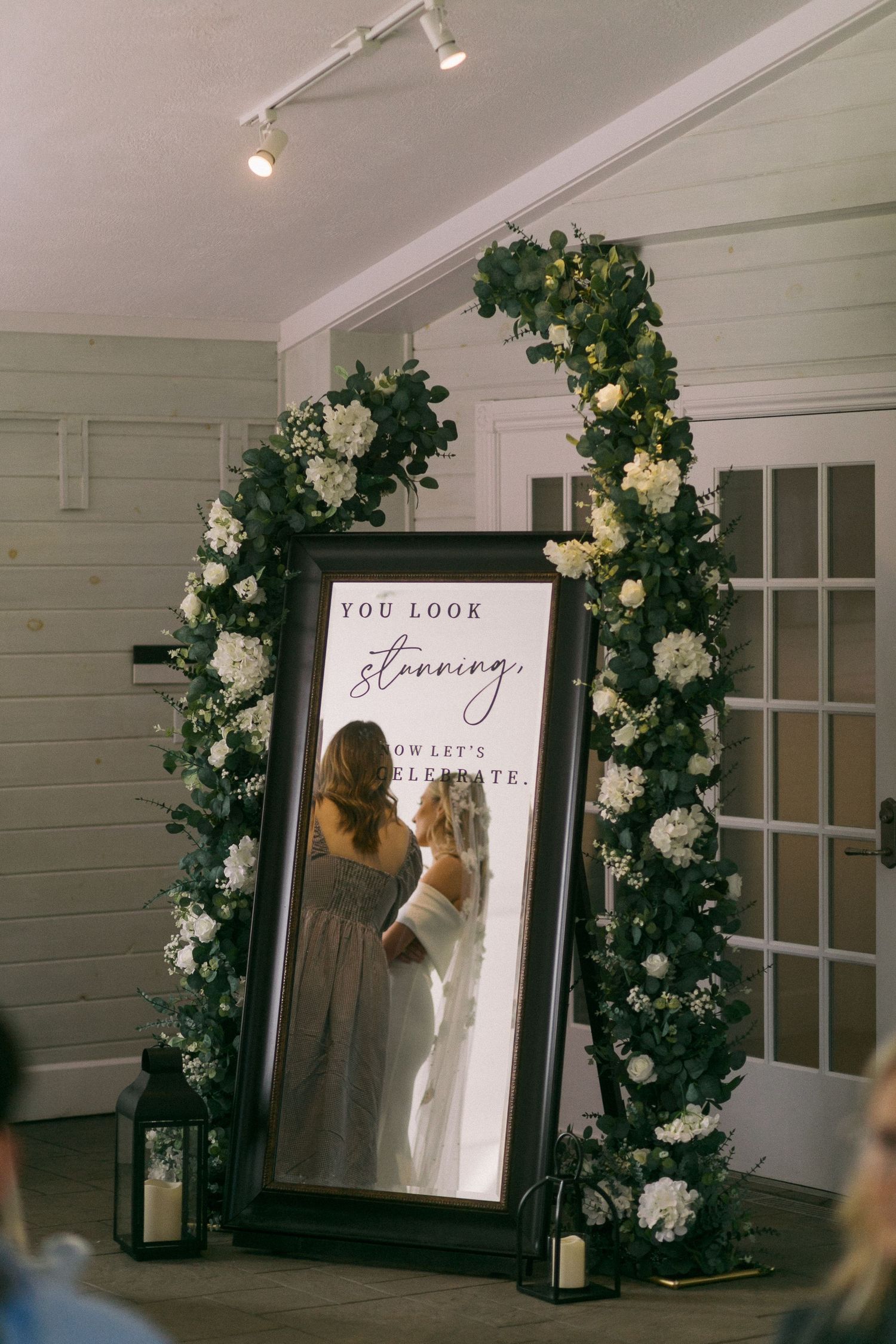 Elegant wedding venue space decorated with climbing floral arrangements and framed artwork.