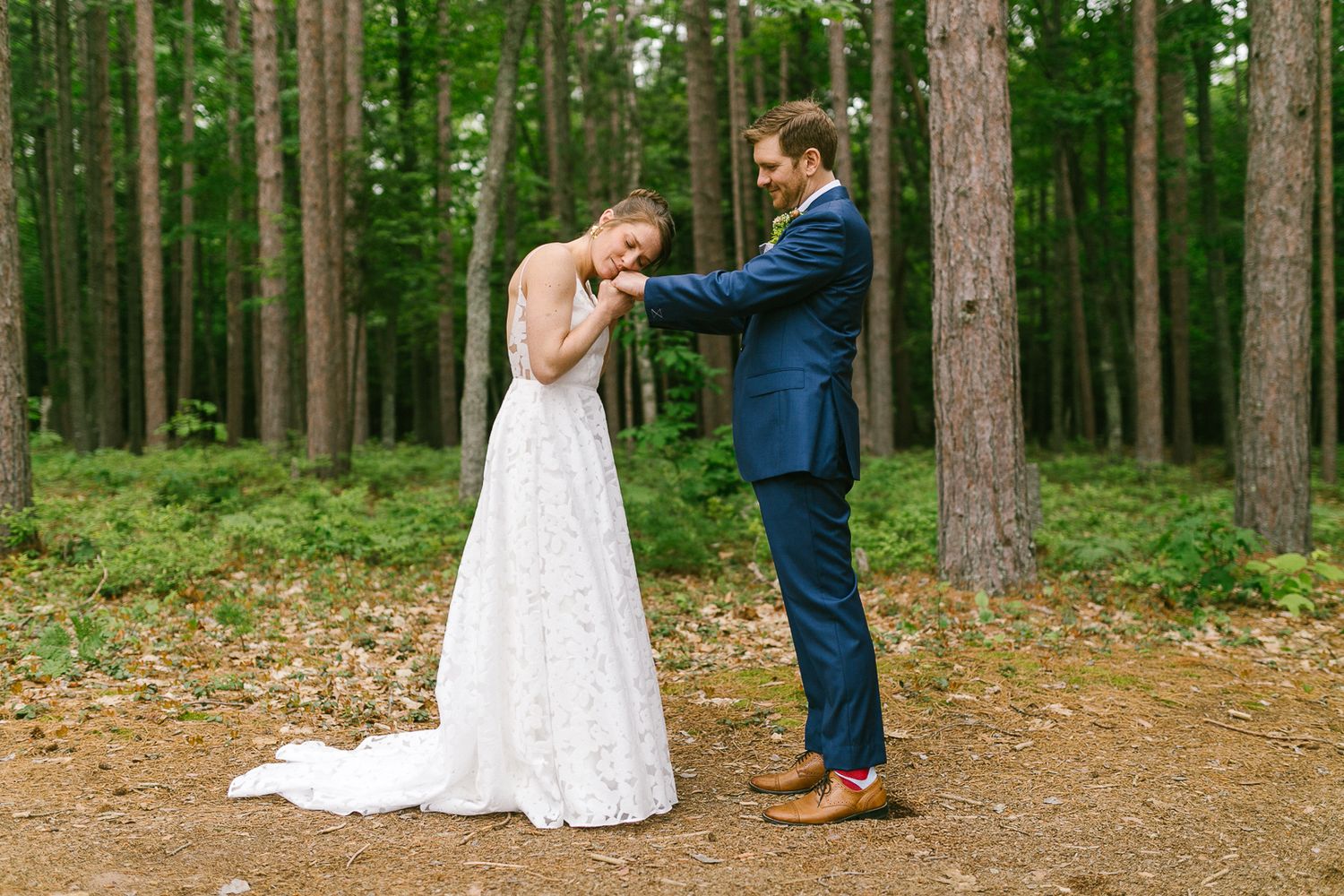 A couple shares an intimate moment in a lush green forest setting.
