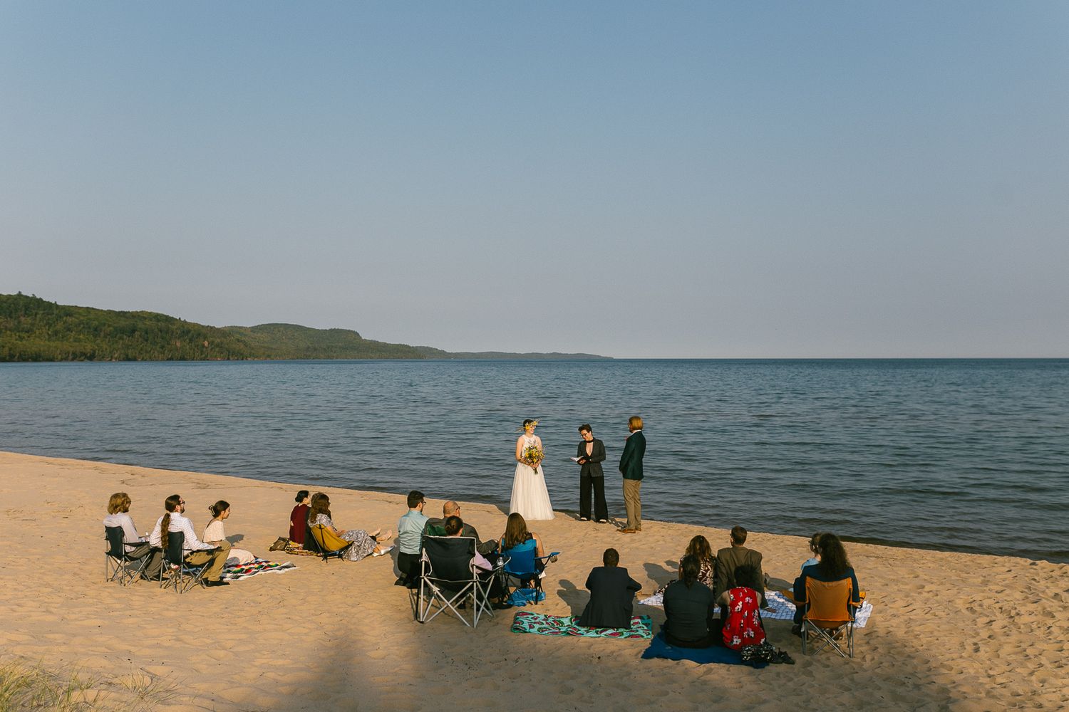Guests gather on a scenic beach at sunset for a waterfront celebration.