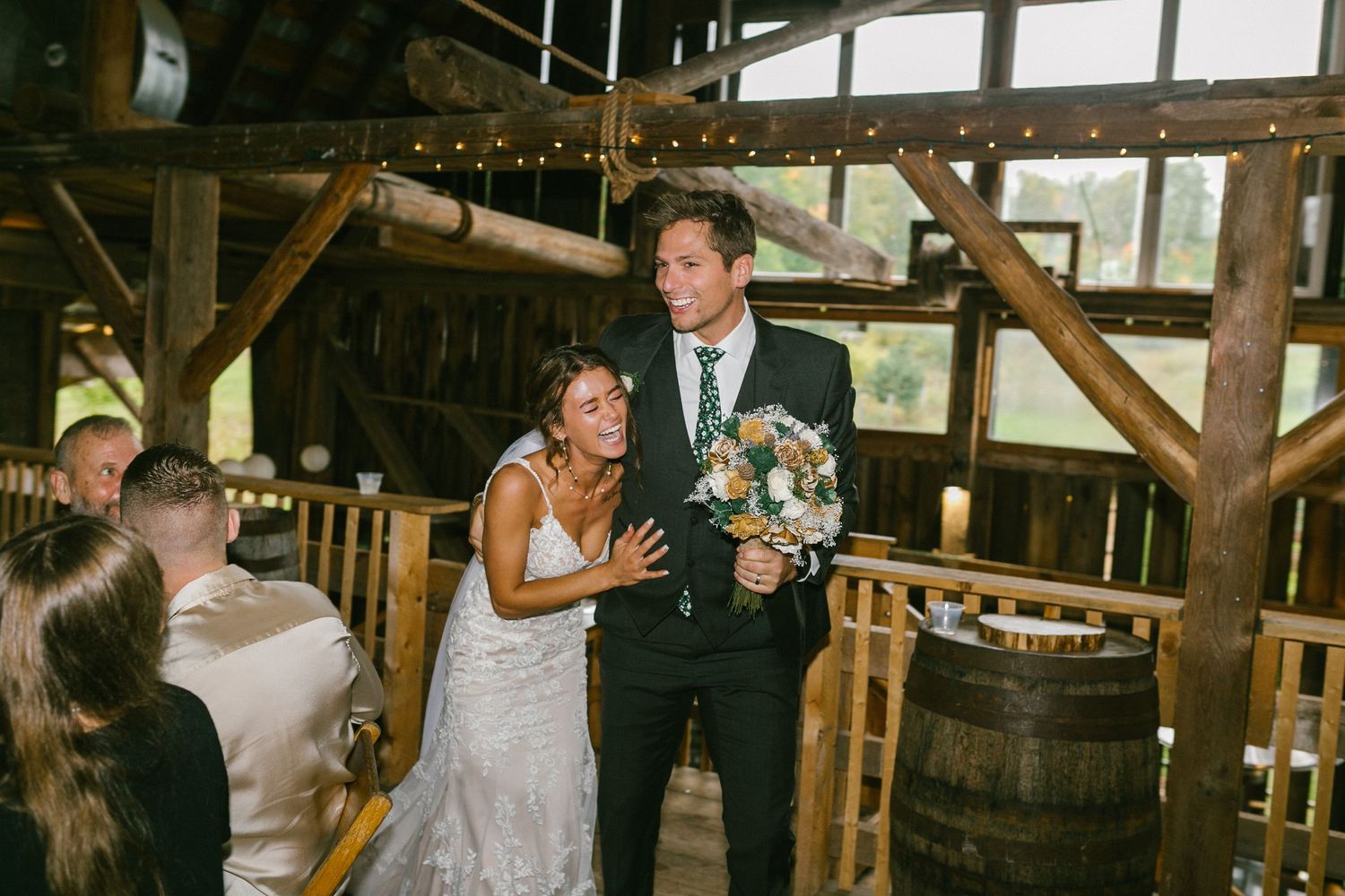A rustic barn wedding celebration with string lights and wine barrels creating a cozy atmosphere.