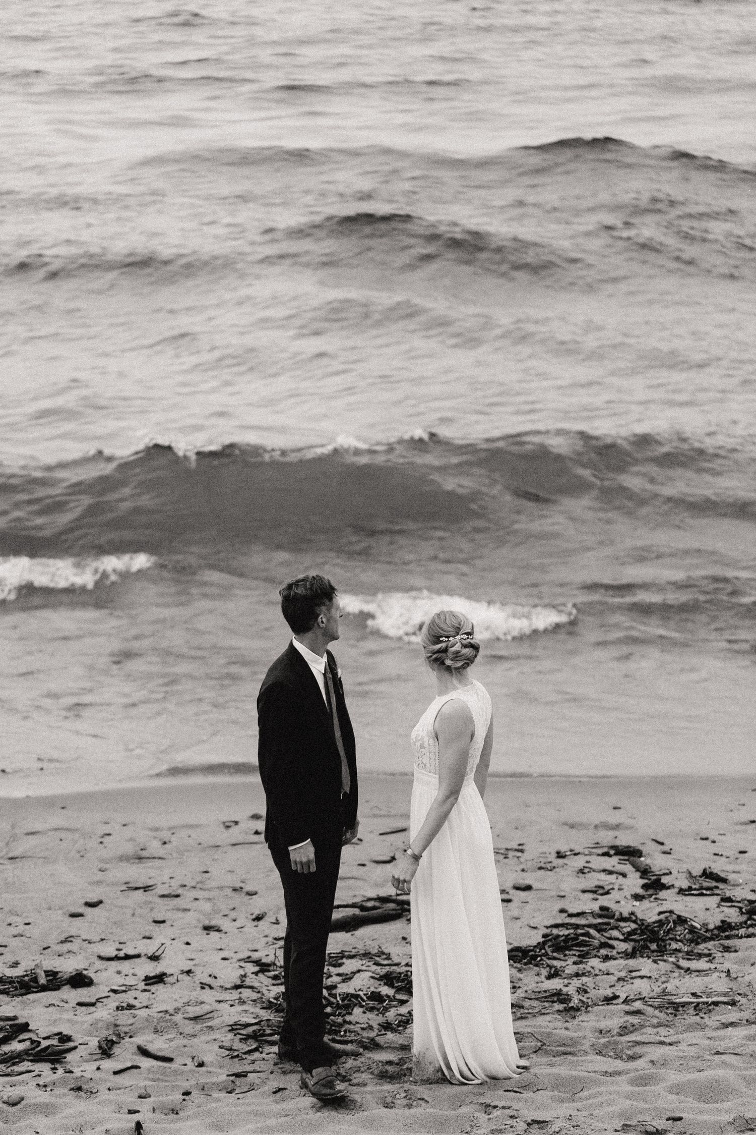 A black and white beach wedding portrait with dramatic waves in the background.