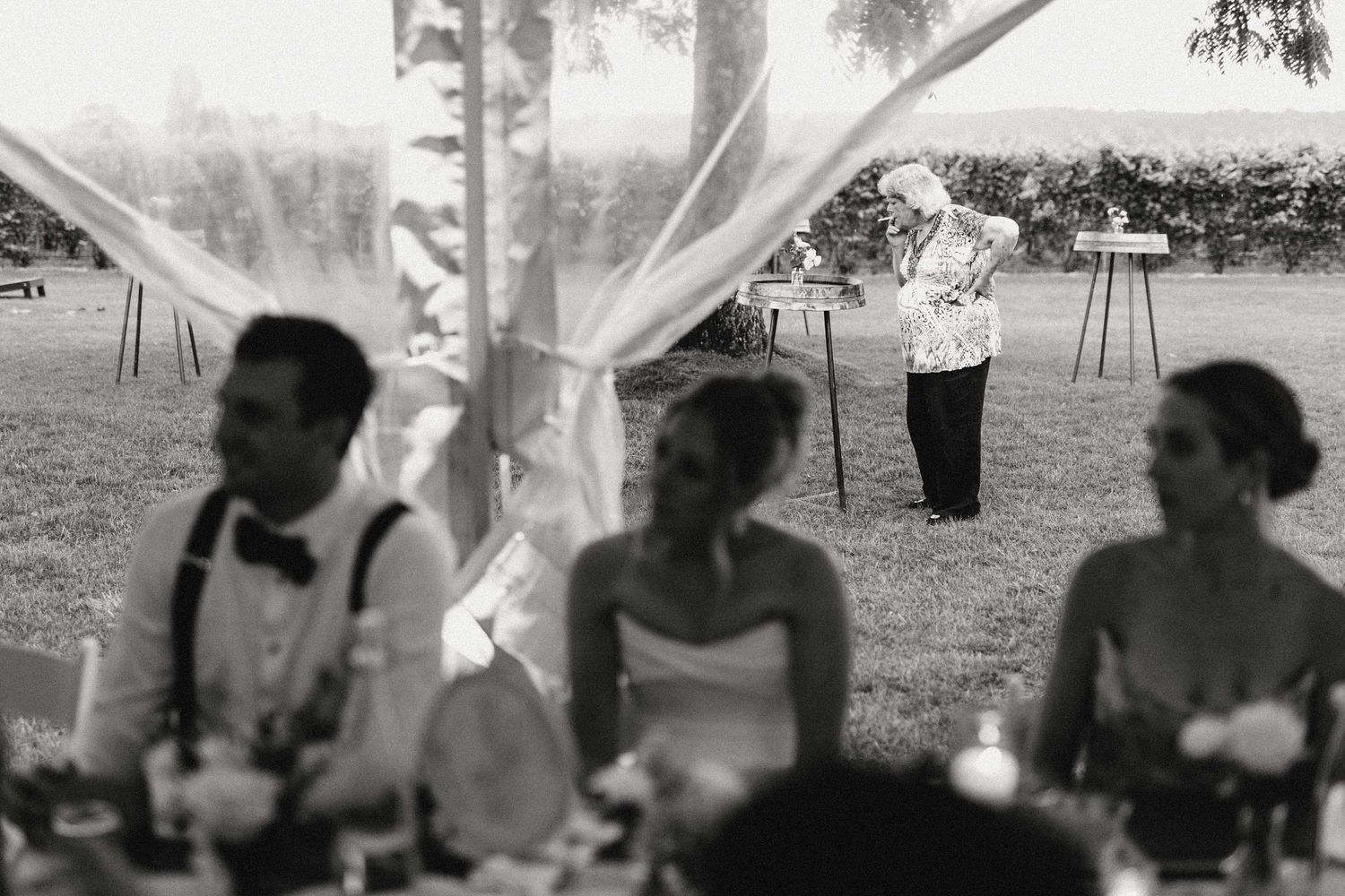 A grandma smokes a cigarette while wedding speeches go on.