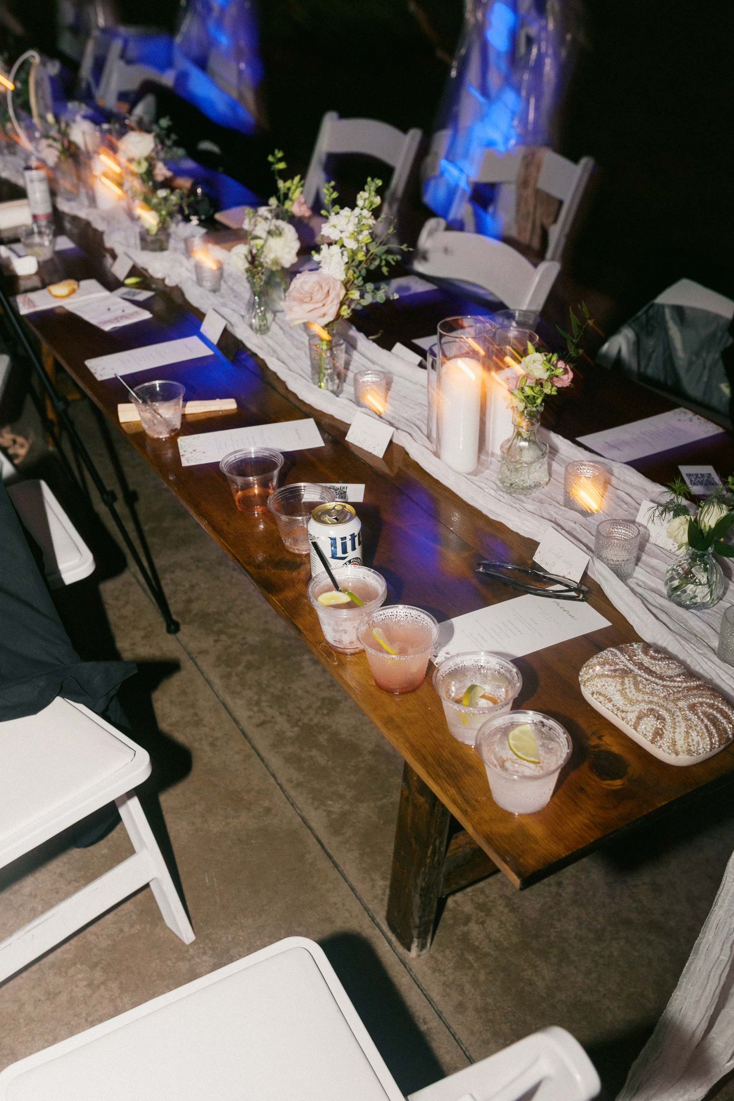 A flash lit wedding reception table decorated with white linens, candles, and floral centerpieces creates an elegant ambiance.