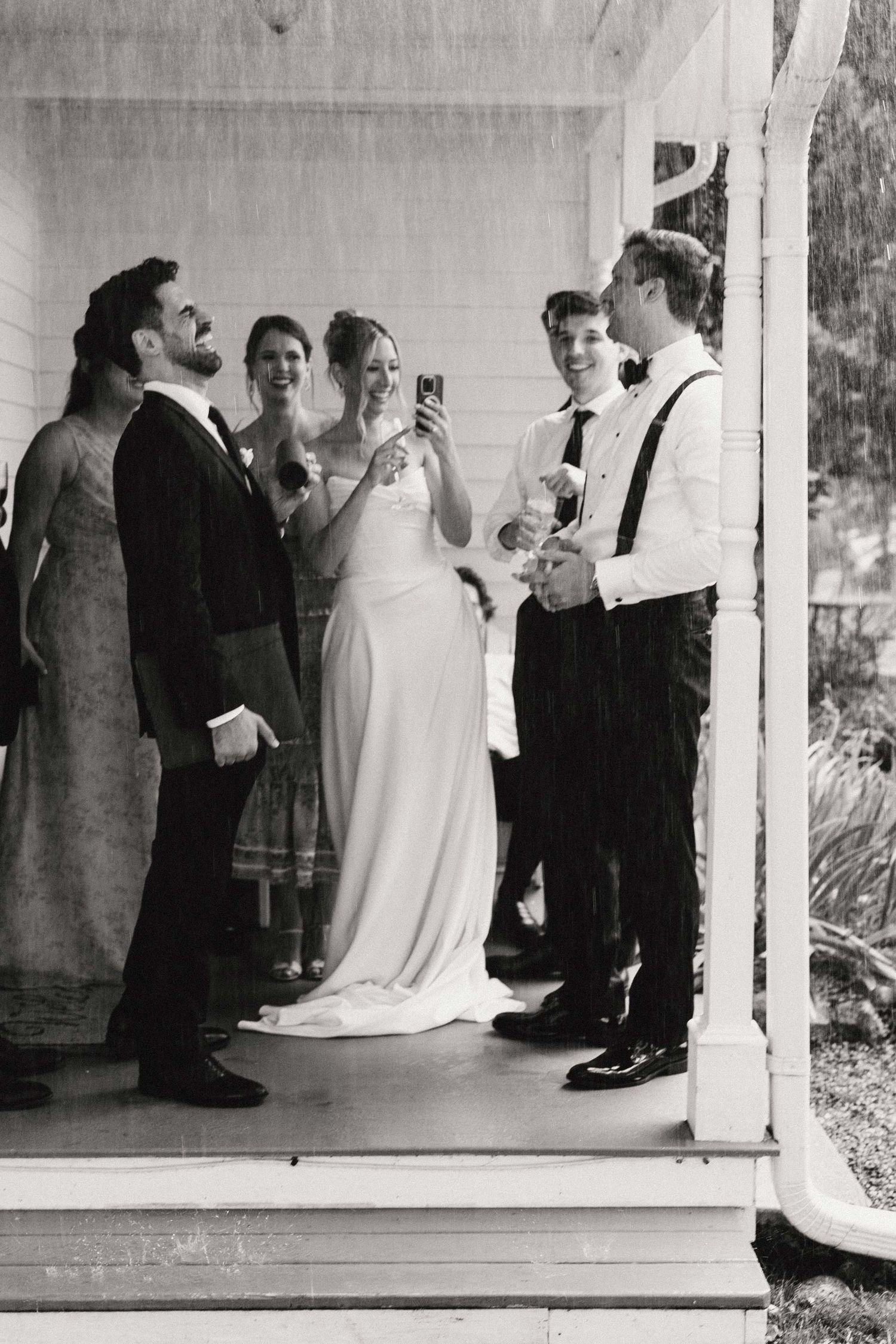 A black and white wedding photo showing a small group gathered on a porch during an intimate ceremony.