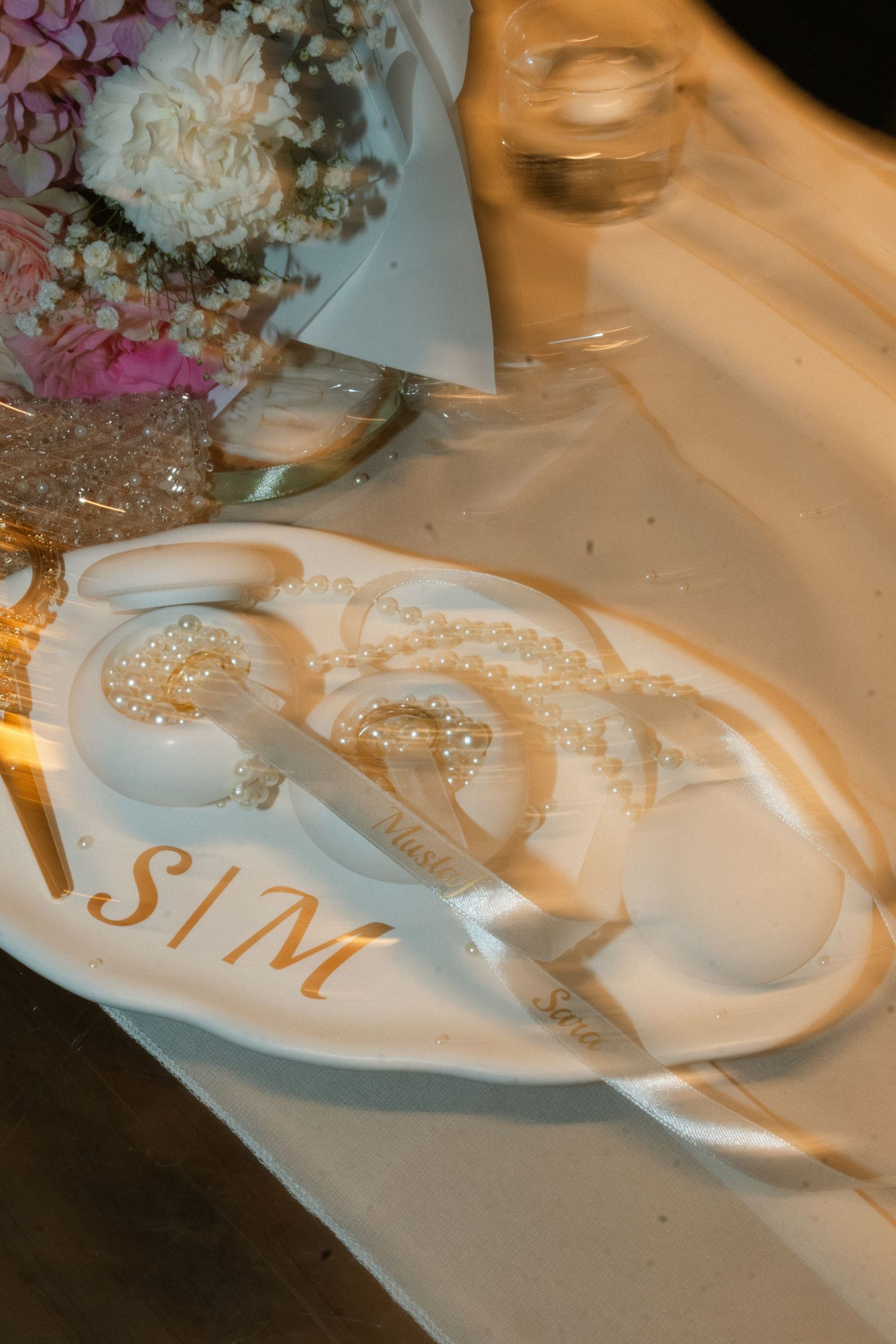 Elegant wedding ring dish with S|M monogram, pearl details, and cake server set on white tablecloth.