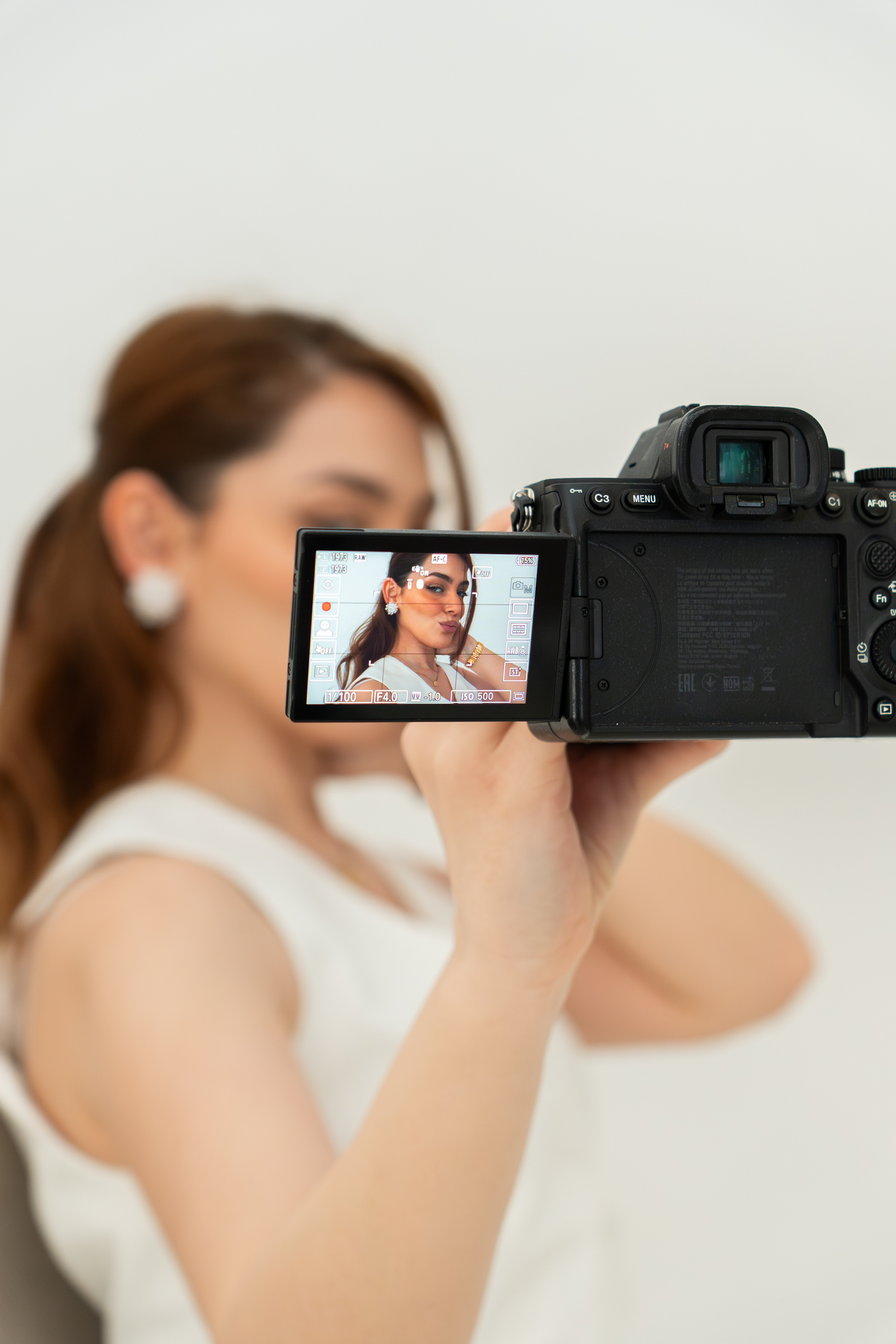 Photographer holds camera displaying portrait of woman with sunglasses on flip screen.